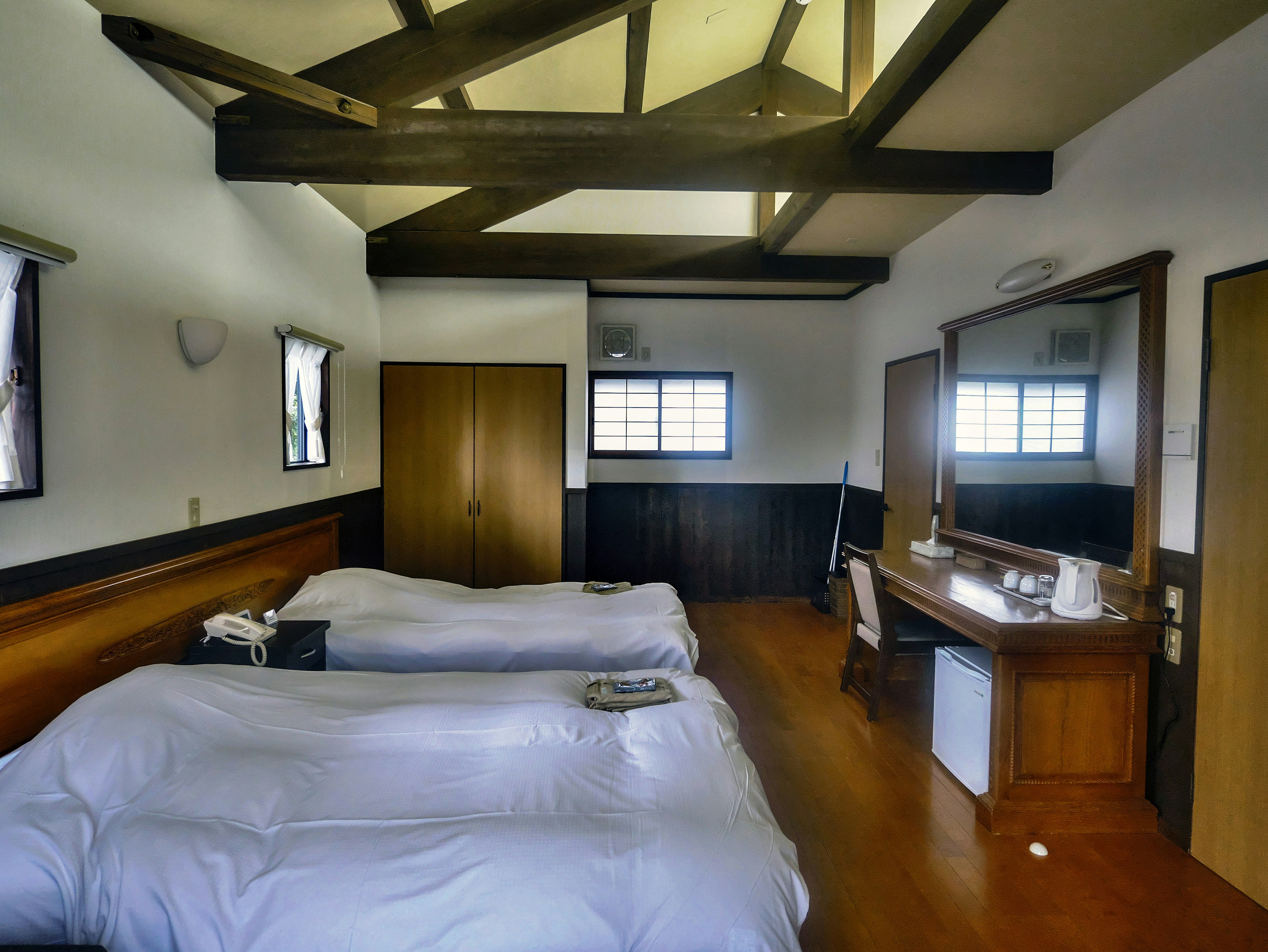 Bright bedroom featuring two beds and a wooden-beamed ceiling