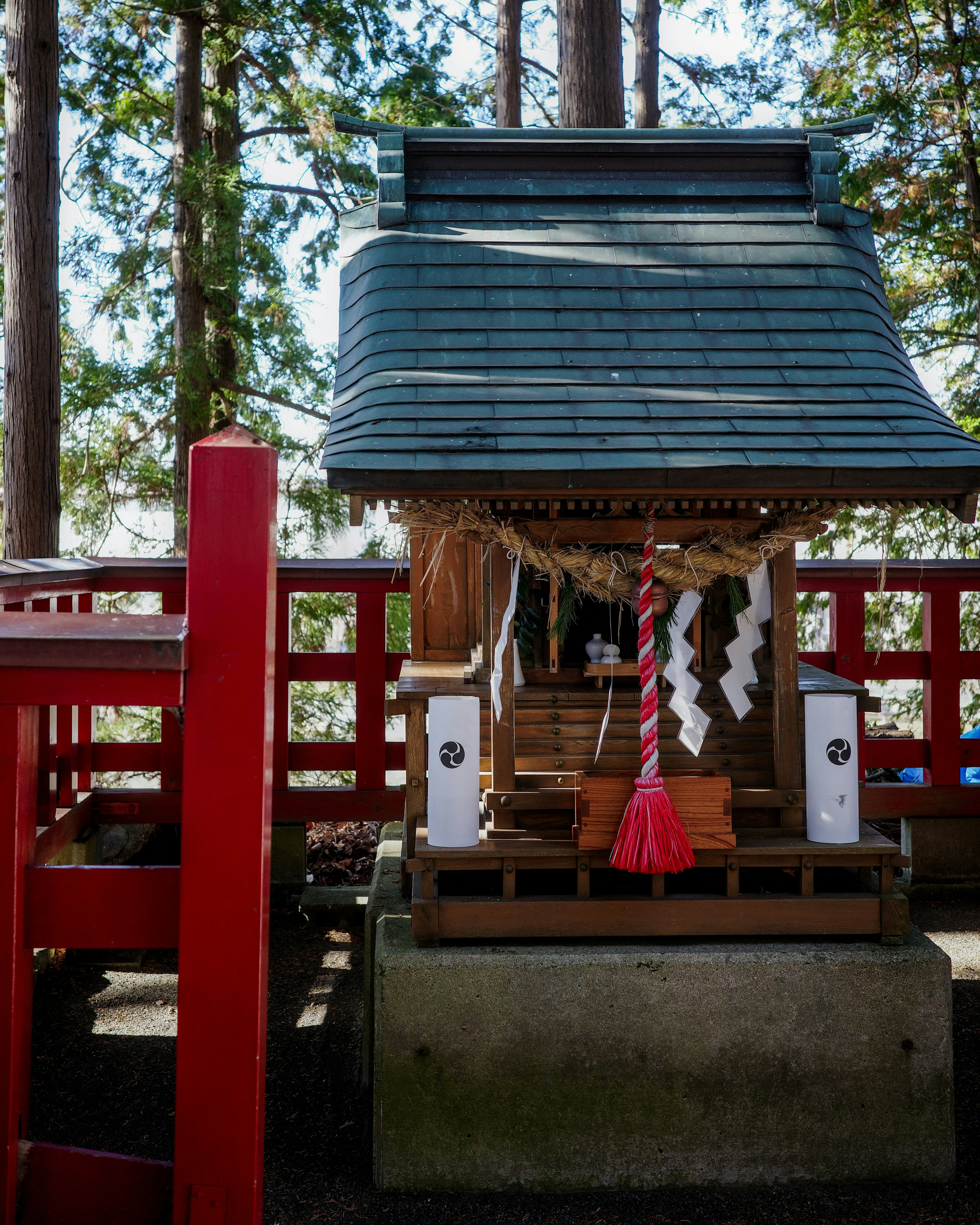 神社の小さな社と赤い鳥居がある風景