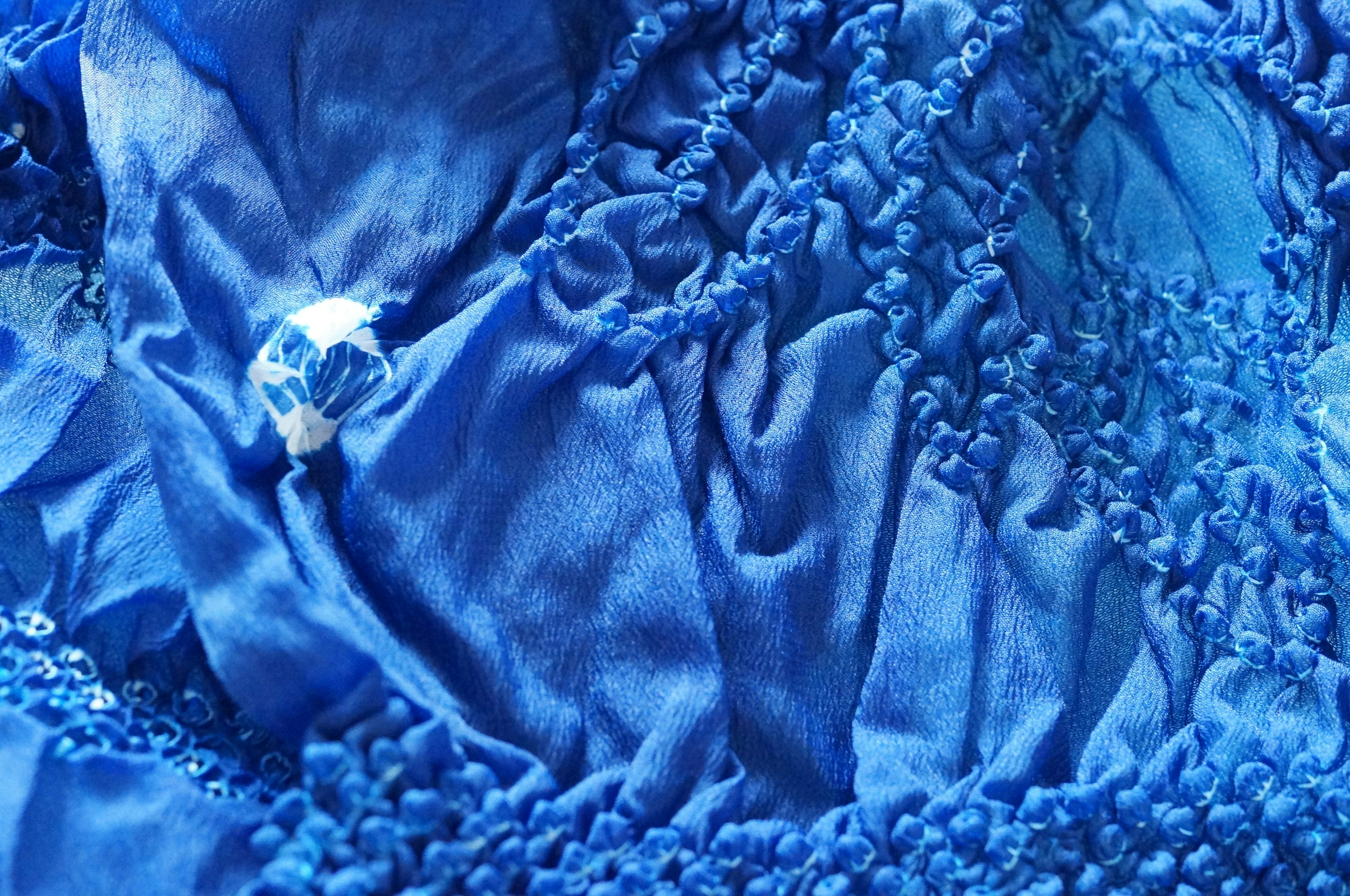 Textured blue fabric with intricate folds and sheen