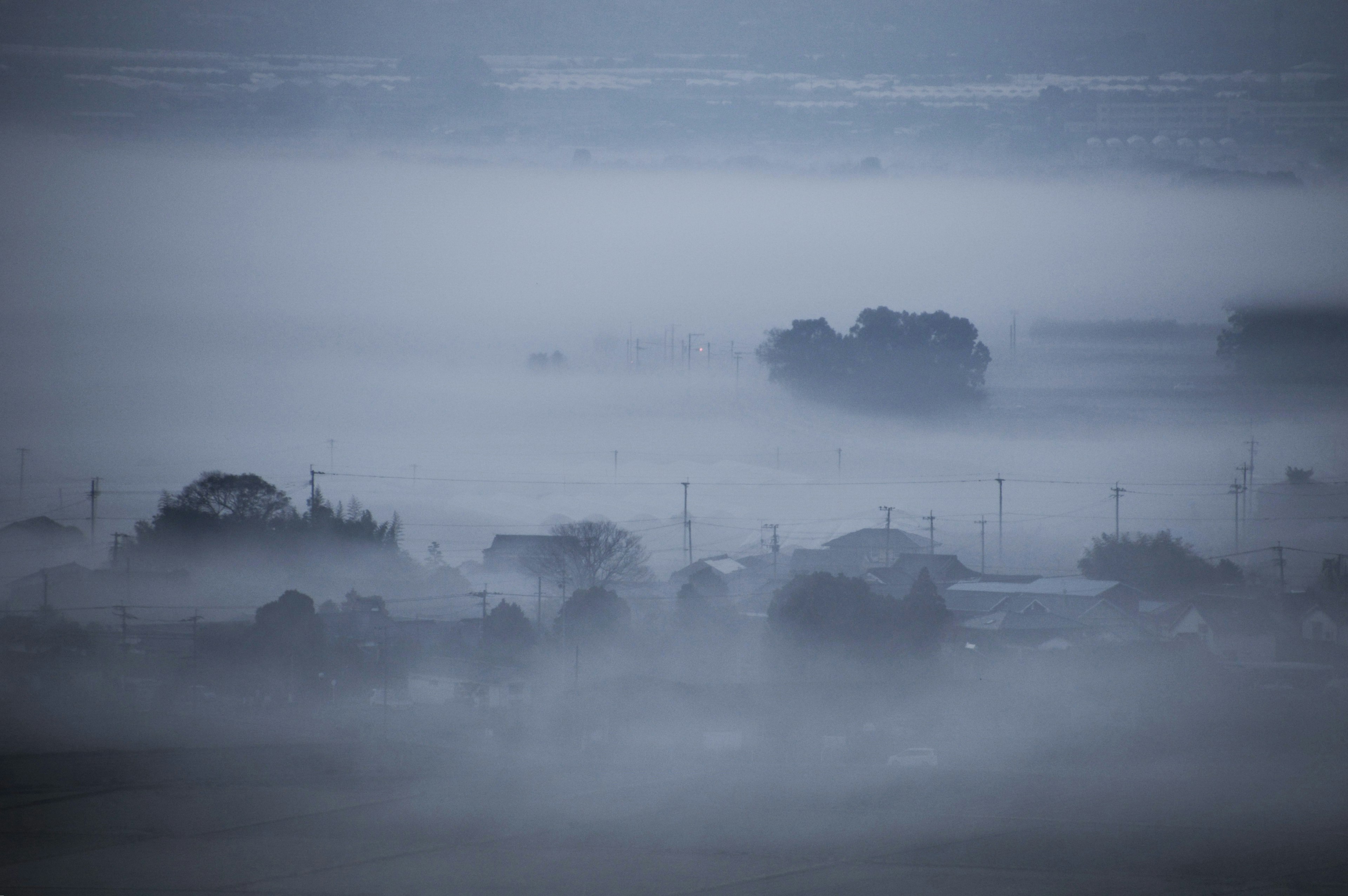 A tranquil landscape enveloped in fog with scattered houses