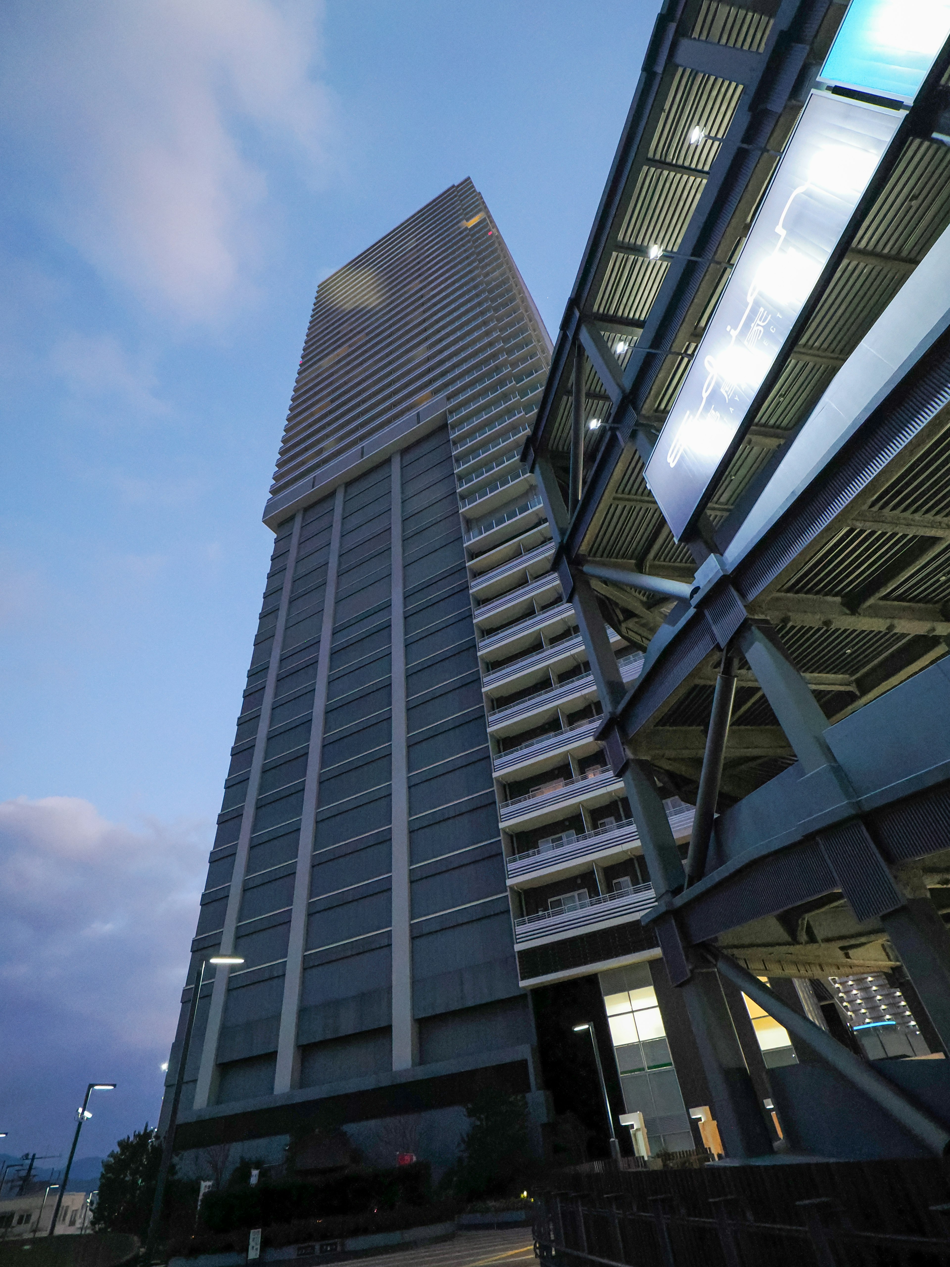 Skyscraper and modern parking structure illuminated at dusk