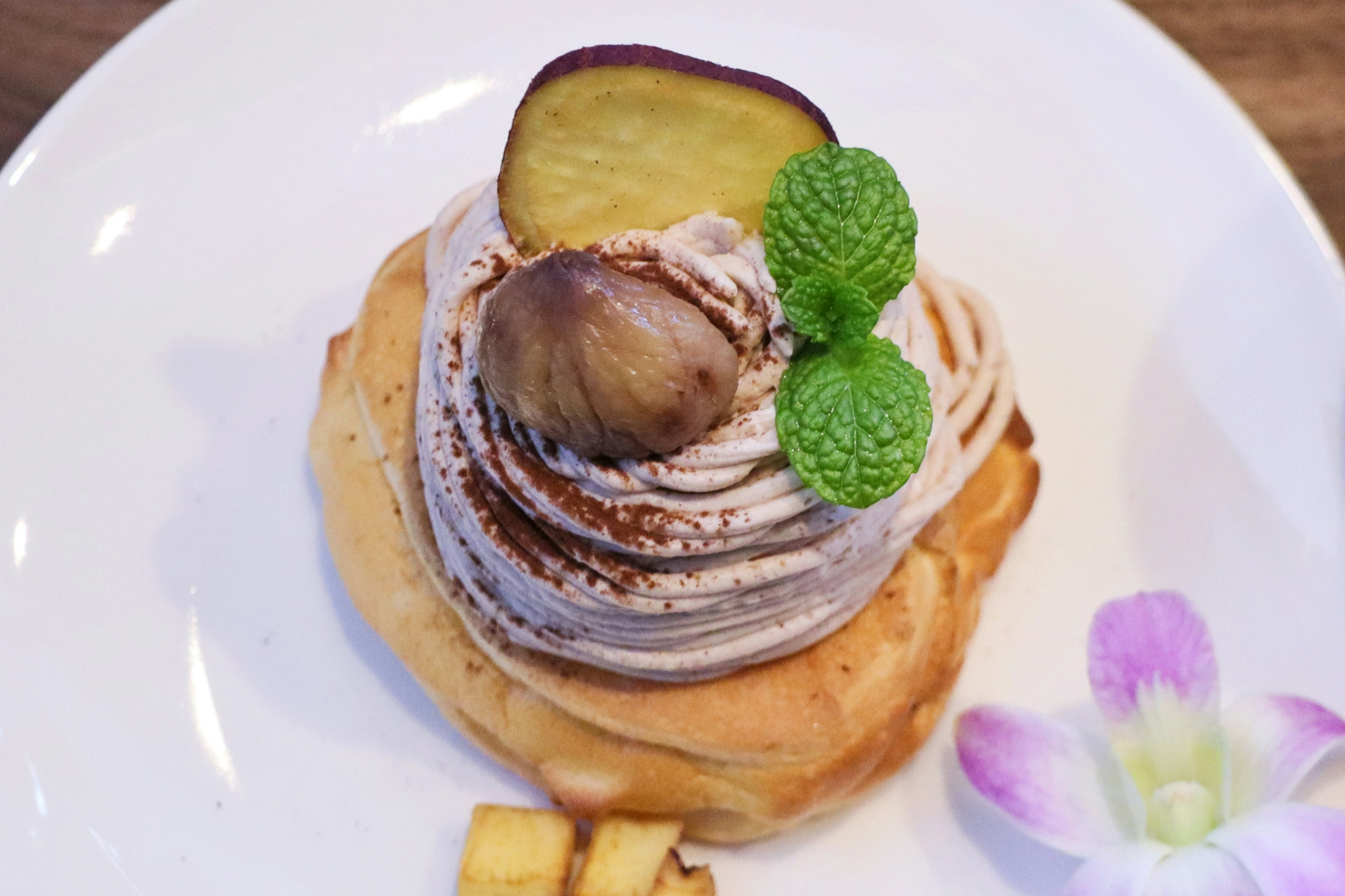 Dessert con crema e castagne guarnito con menta e un fiore viola