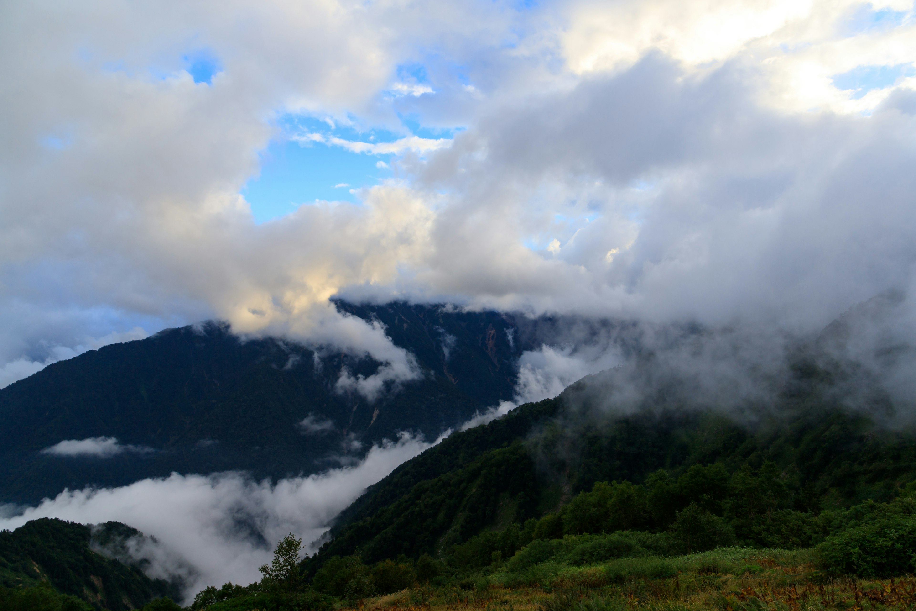 Scenic view of mountains shrouded in clouds with a blue sky