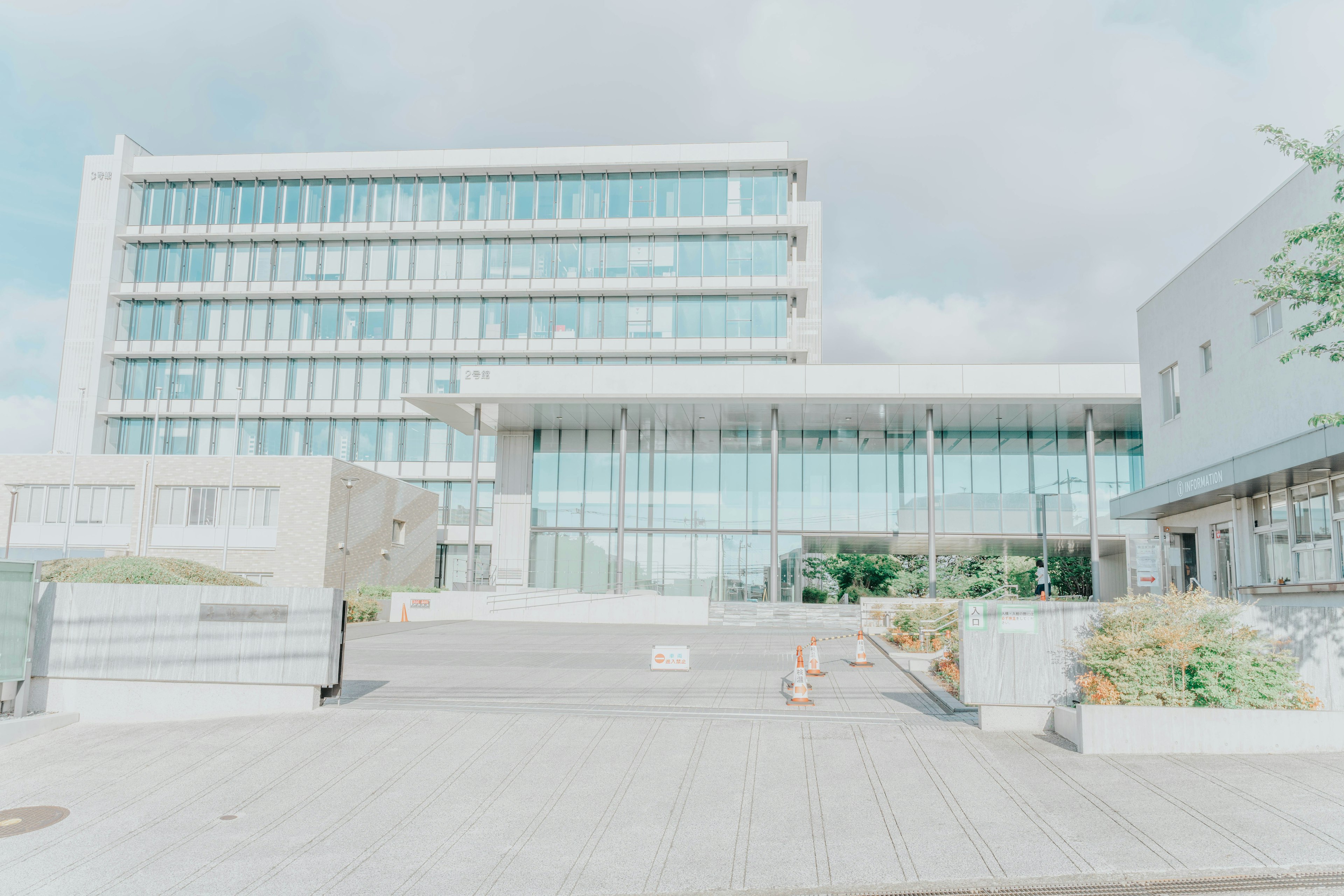 Exterior de un edificio moderno con fachada de vidrio transparente y áreas verdes circundantes