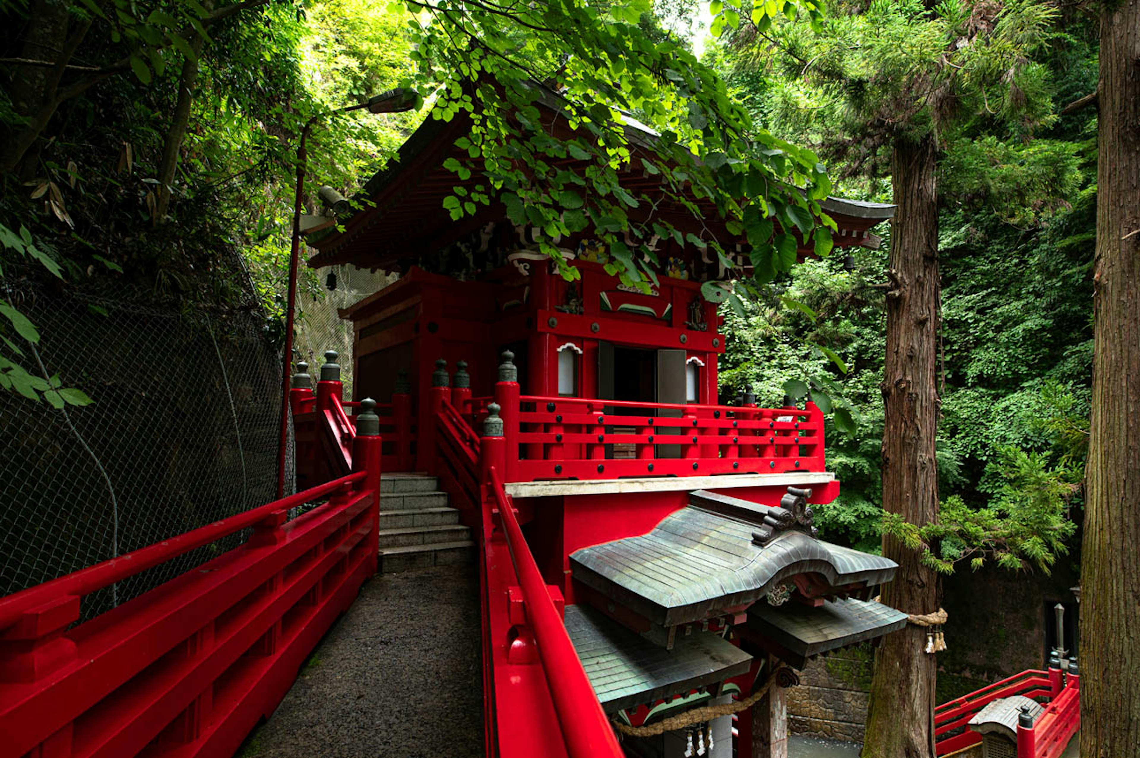 赤い橋と神社が緑に囲まれた静かな風景