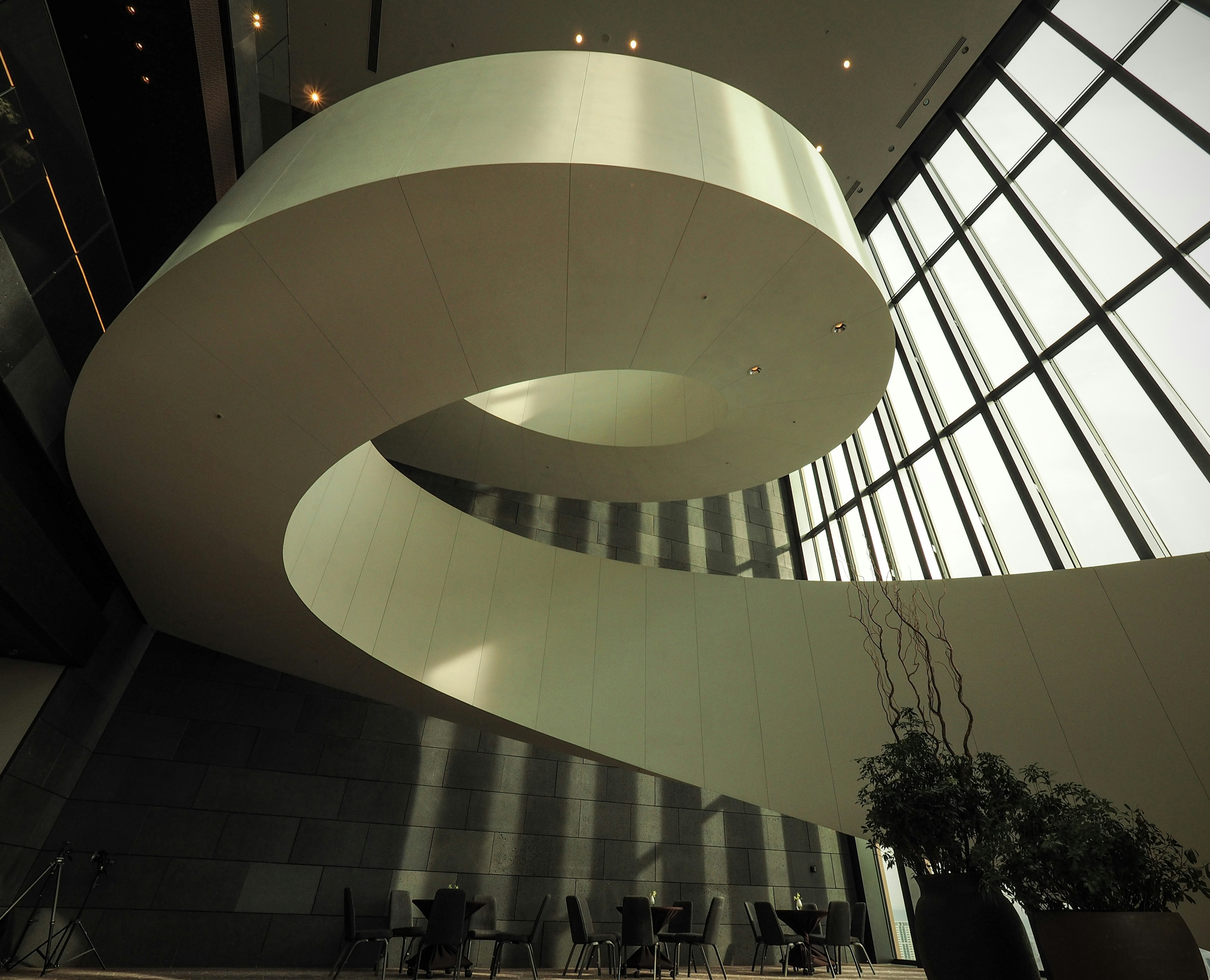 Interior de un edificio moderno con una escalera en espiral suave y grandes ventanas