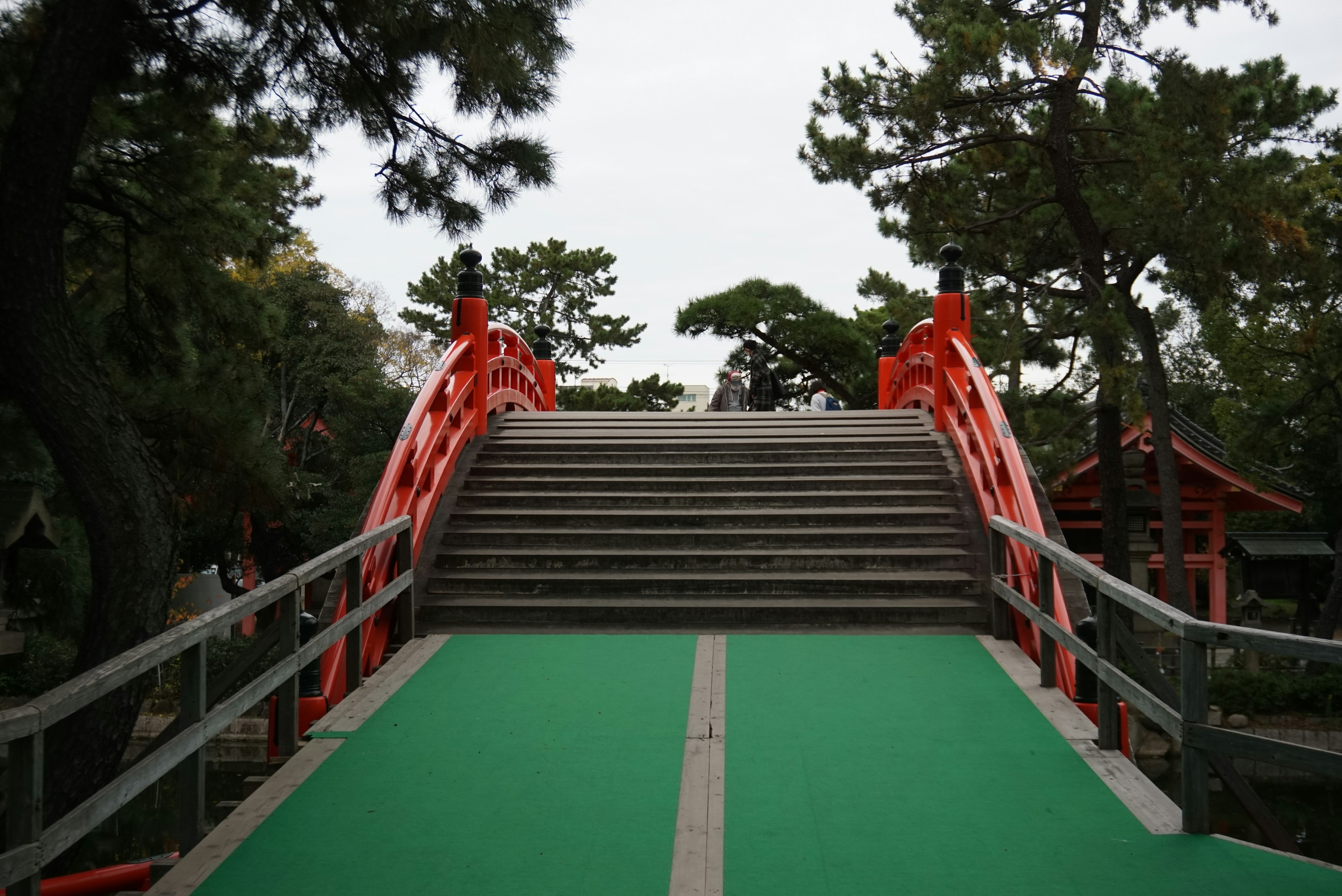 Red bridge with green pathway in a serene landscape