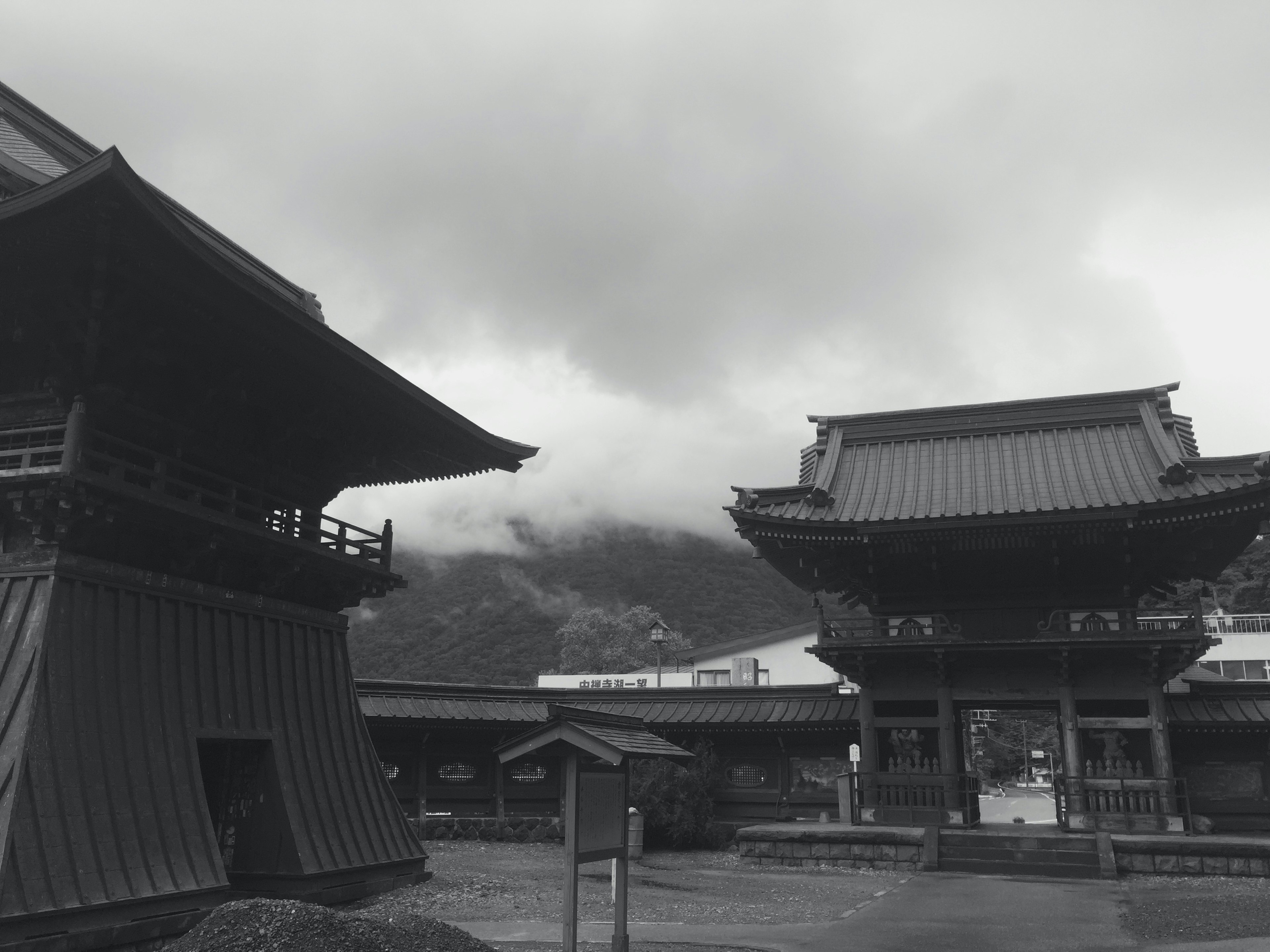 雲に覆われた山を背景にした日本の伝統的な建物の風景