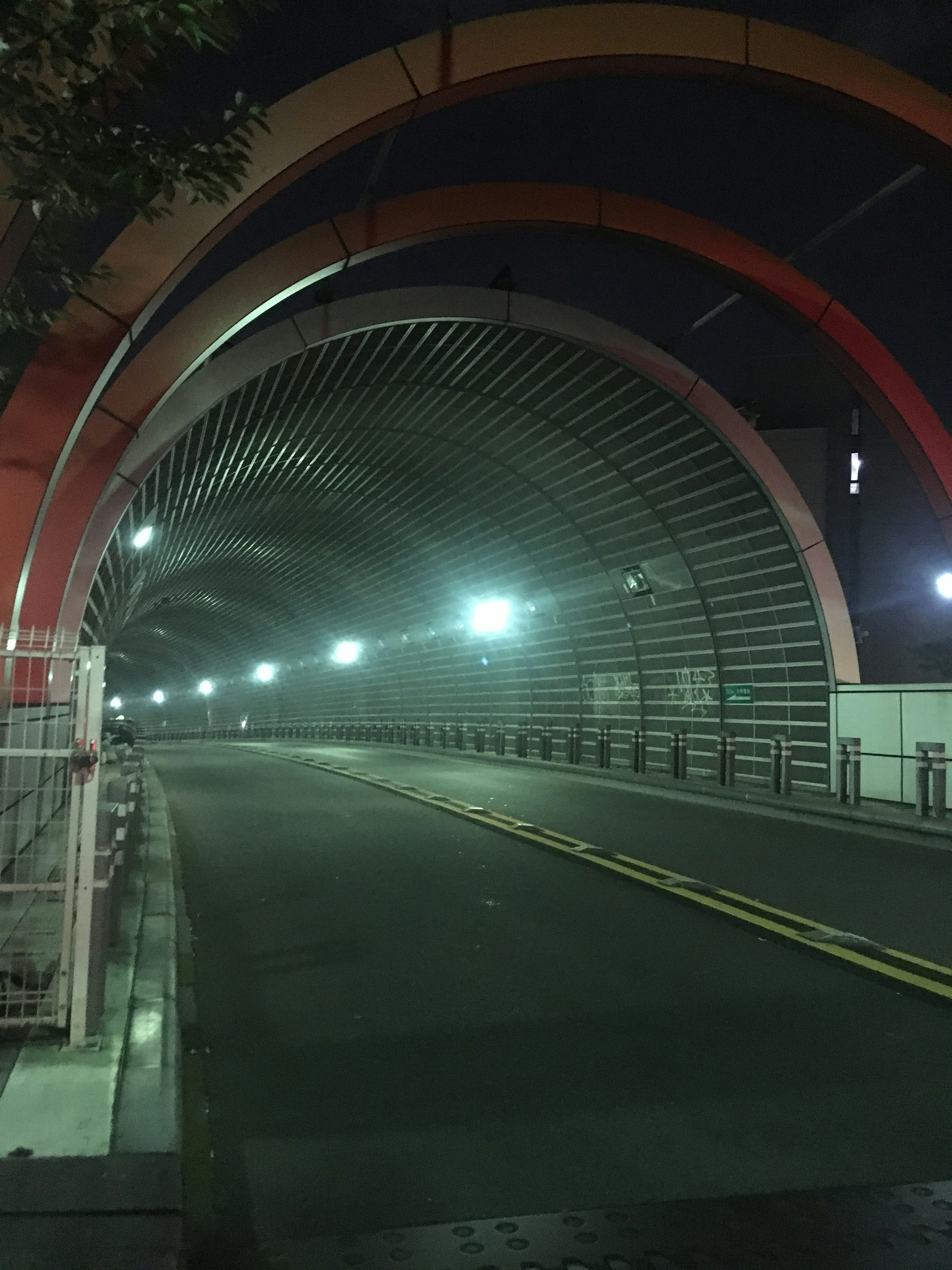 Puente arqueado colorido iluminado por la noche con carretera vacía