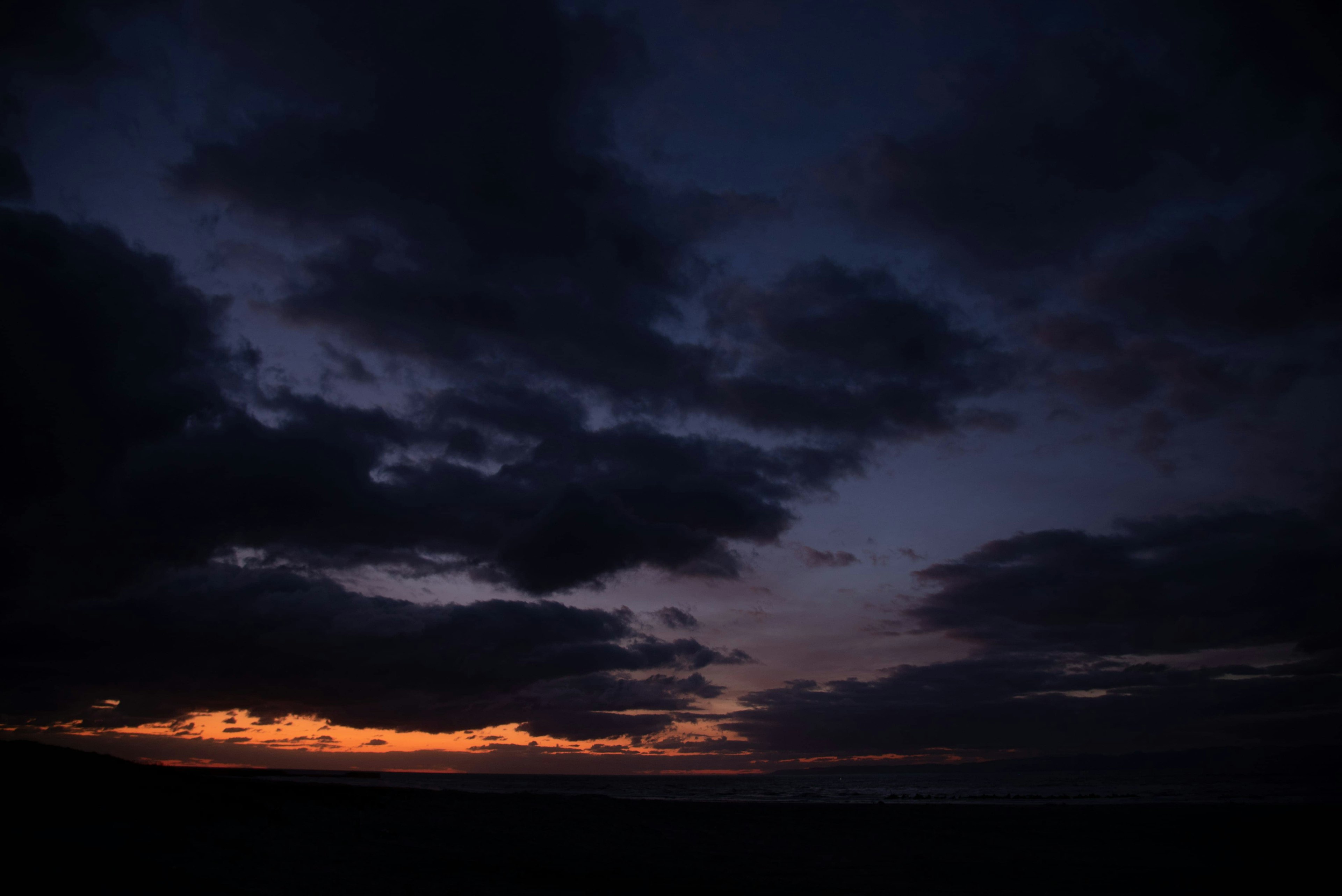 暗い空に浮かぶ雲と薄明かりの地平線