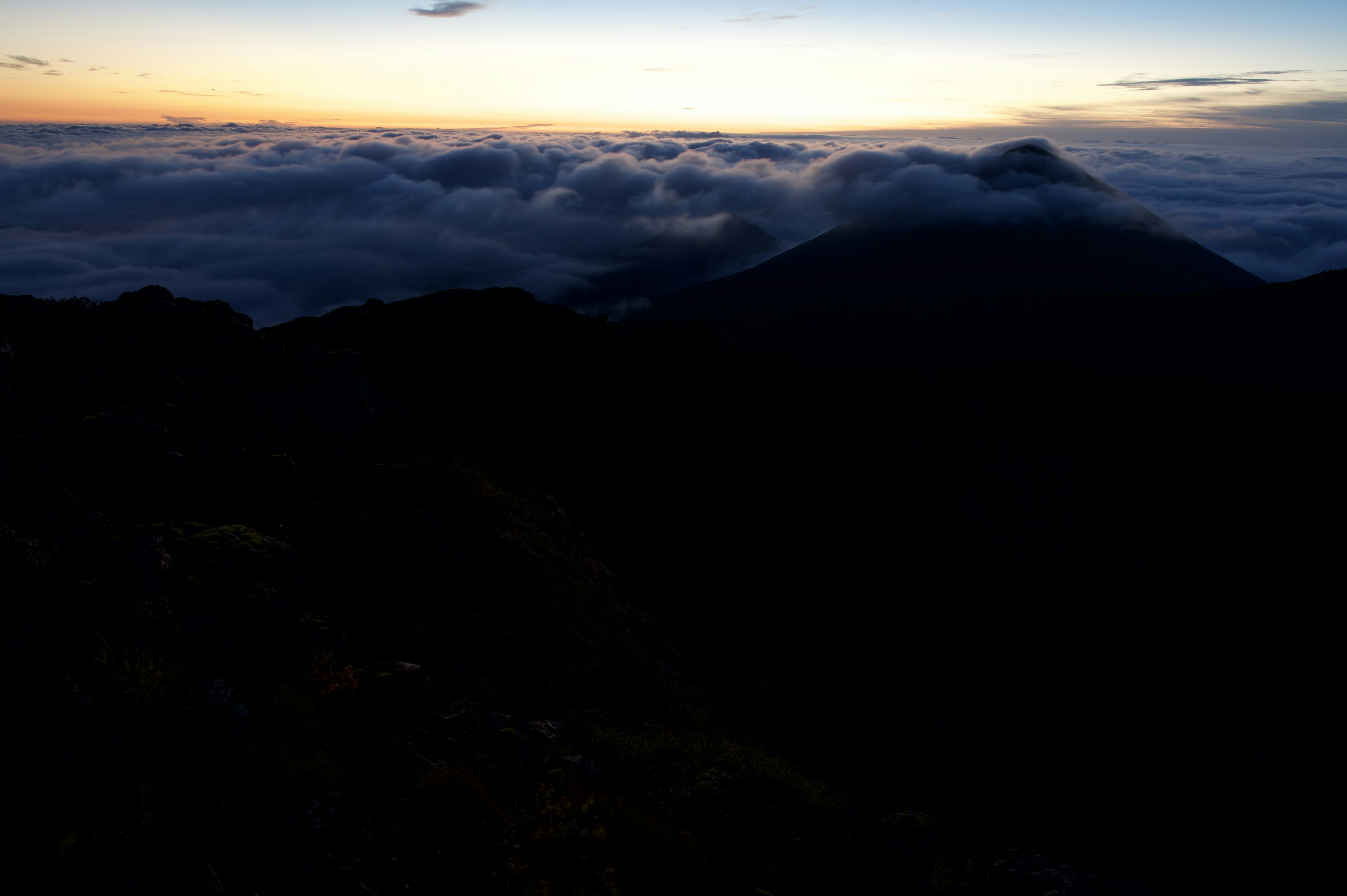 Silhouette of mountains above a sea of clouds at sunset