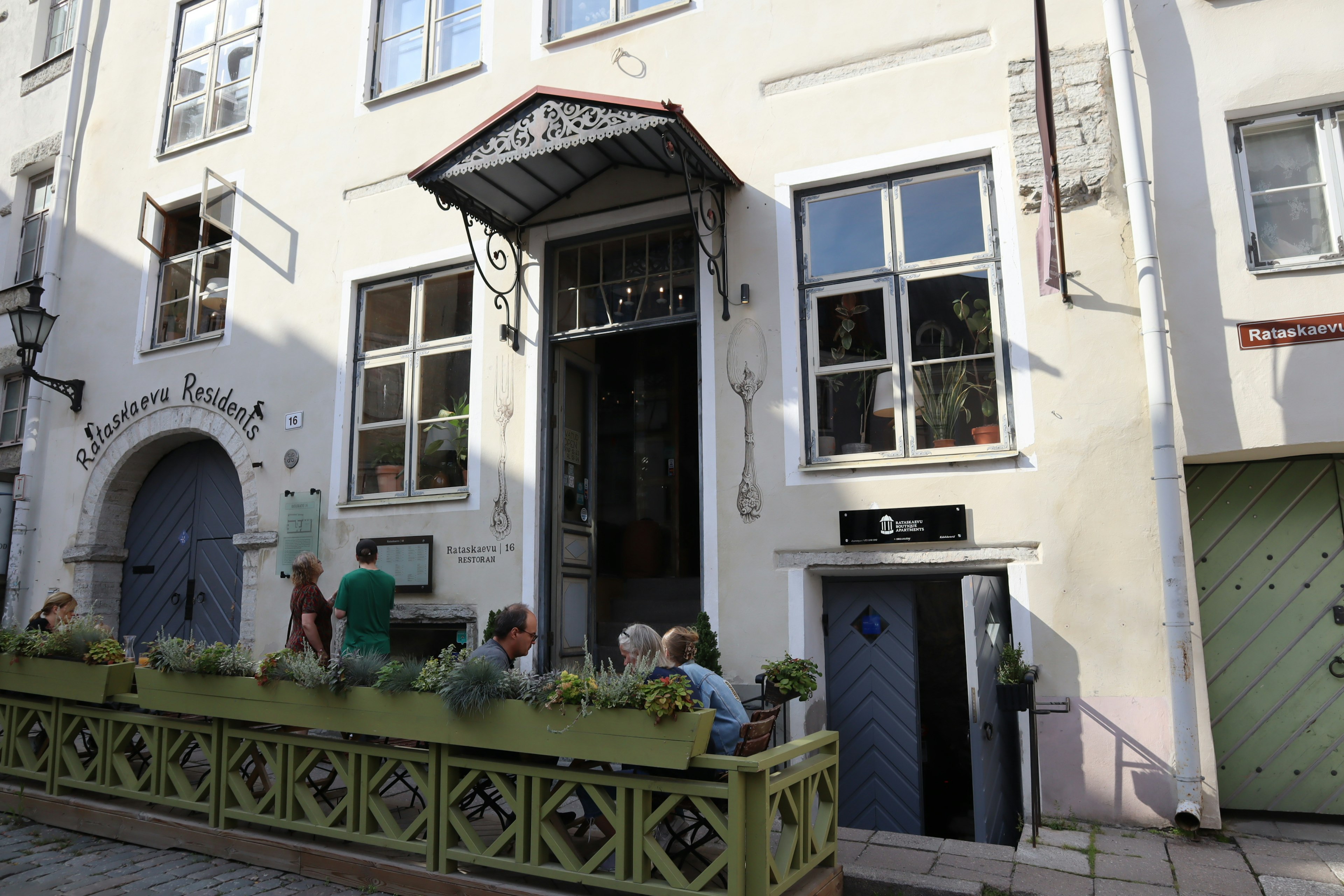 White building with green balcony and people gathered outside