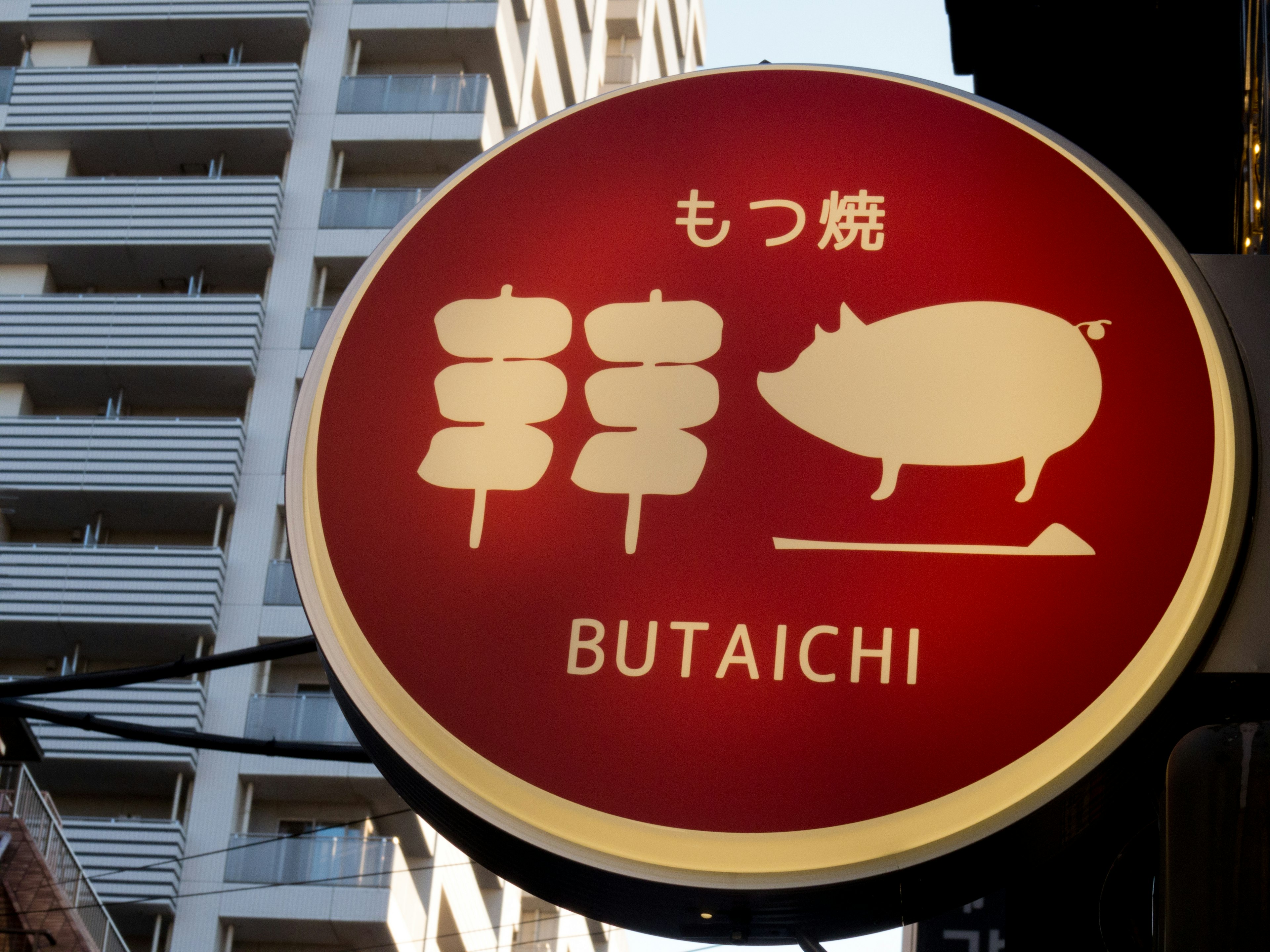 Sign for a pork restaurant featuring illustrations of skewers and a pig