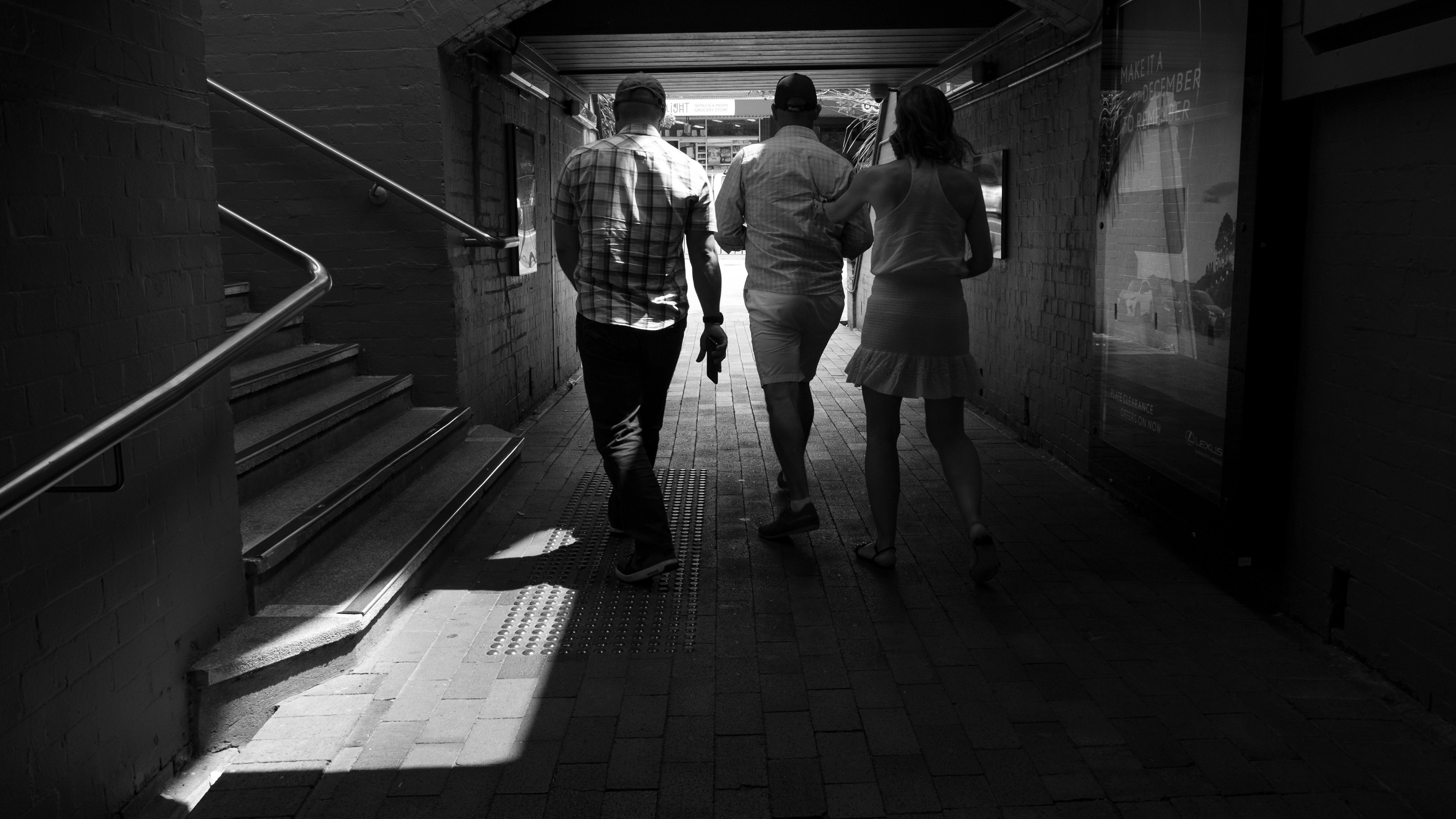 Tres personas caminando a través de un túnel en blanco y negro