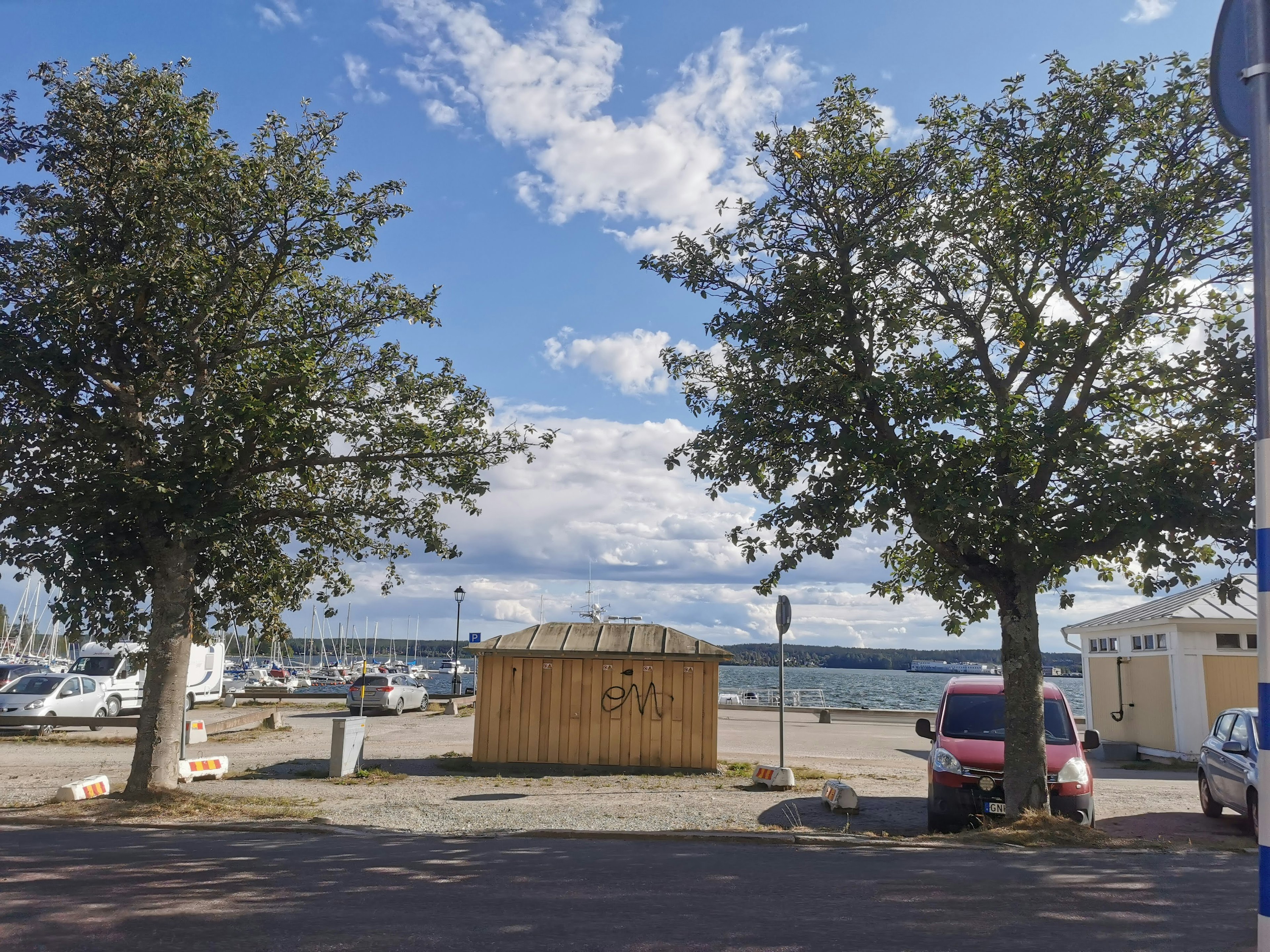 Wooden shed near the waterfront with trees and boats