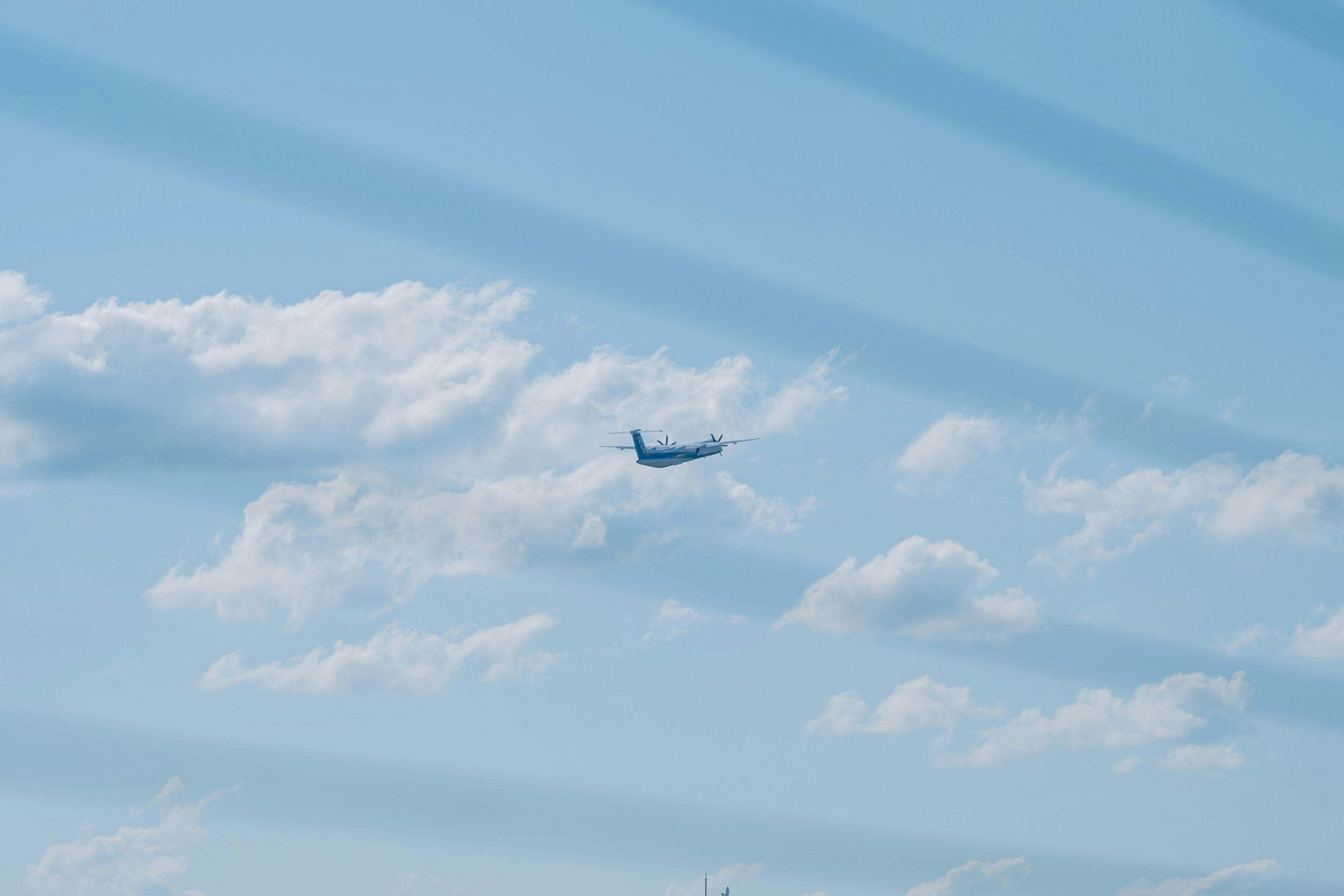 Avión volando en un cielo azul con nubes blancas