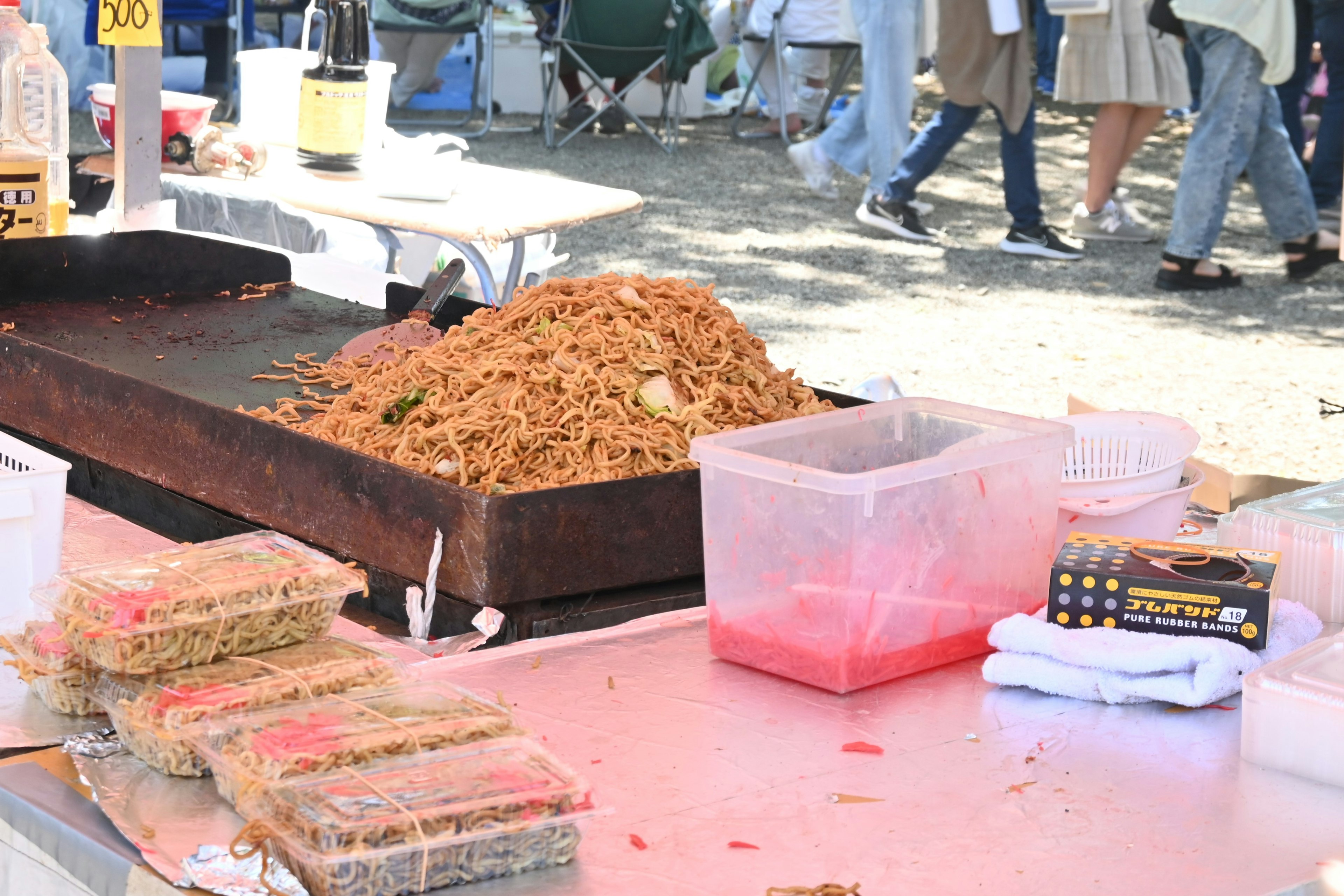 Scena di un chiosco di cibo con noodles saltati su una griglia e contenitori vicini