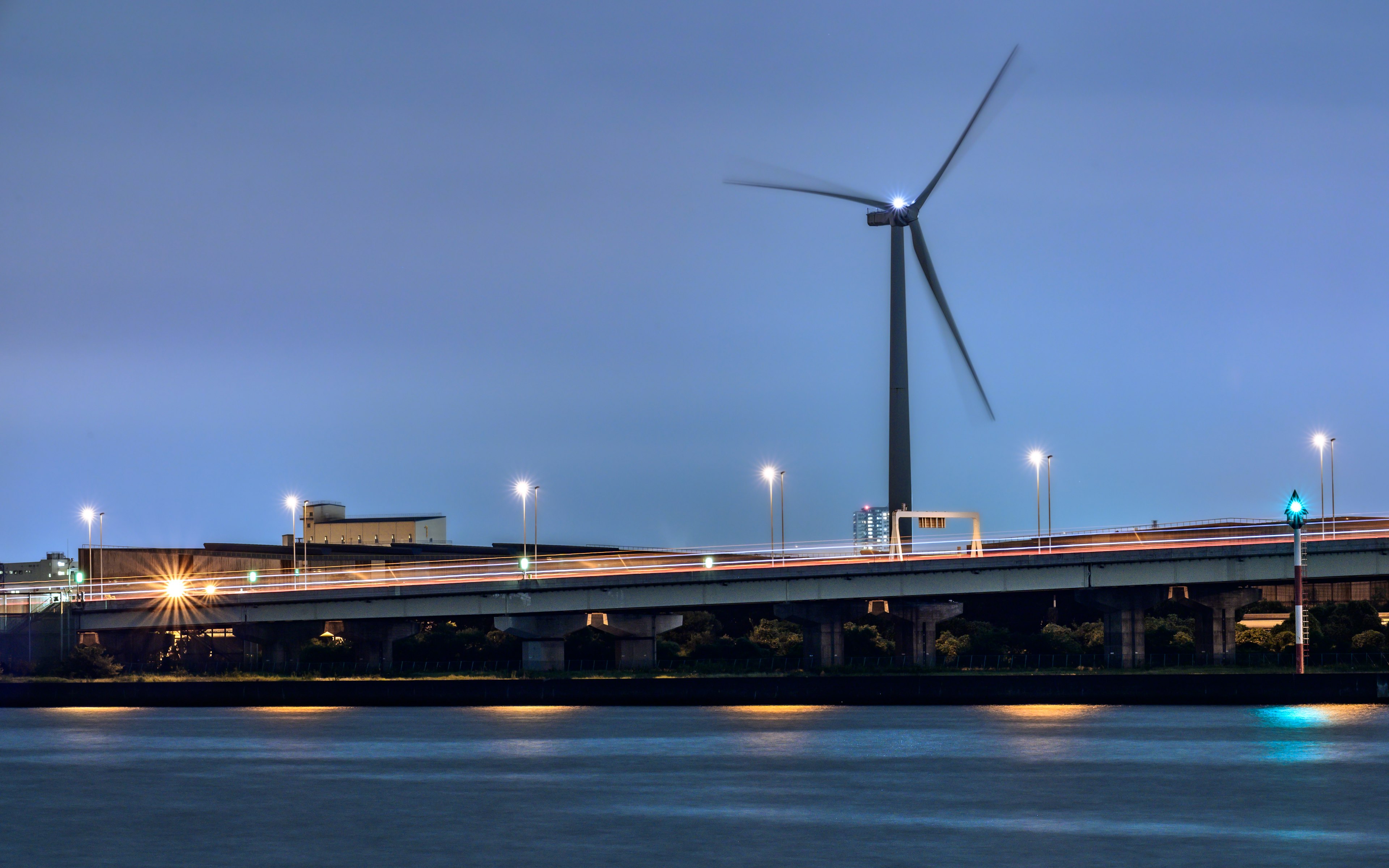 夜景中的風力發電機和沿河的橋