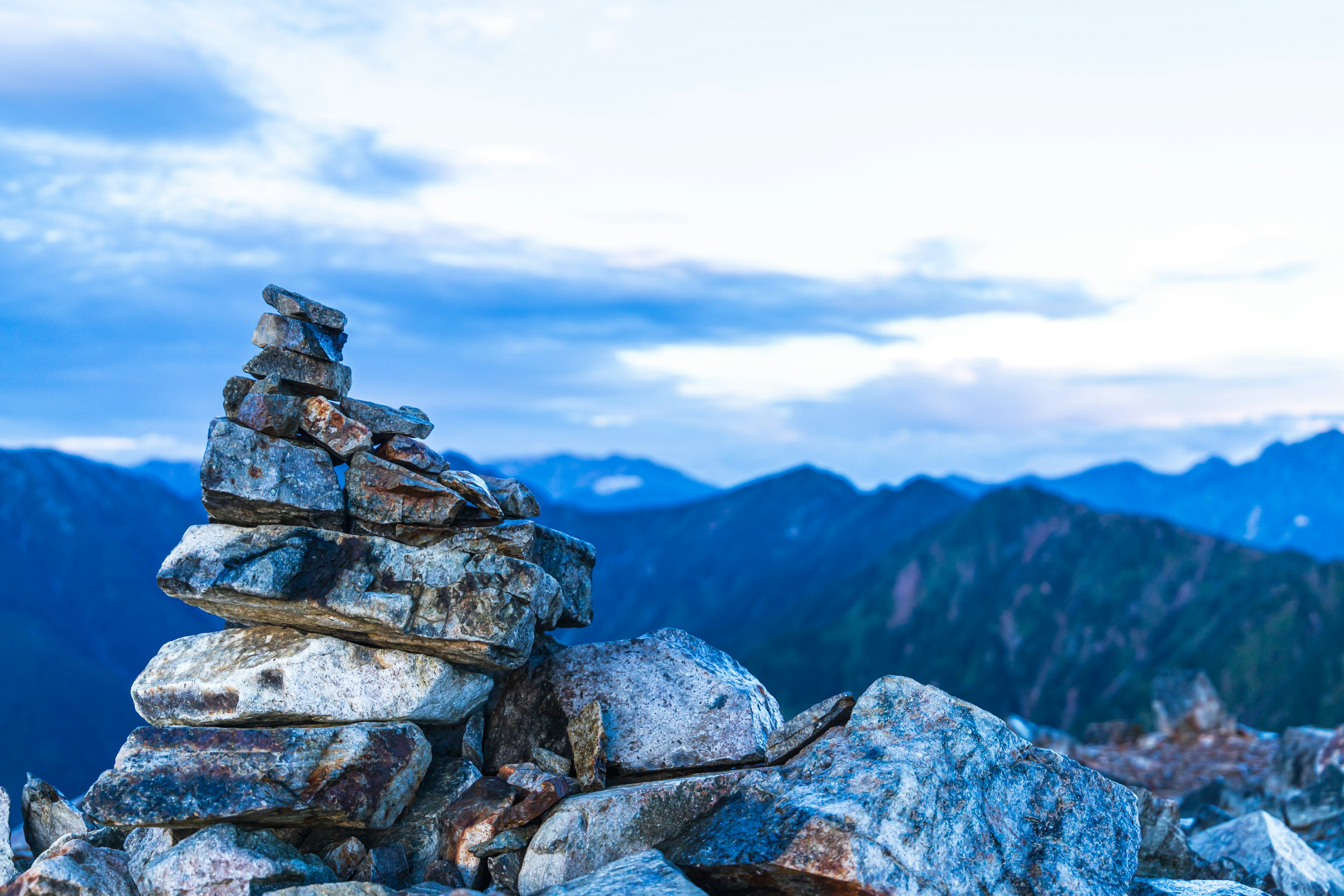 Stone cairn at a mountain summit with a blue sky