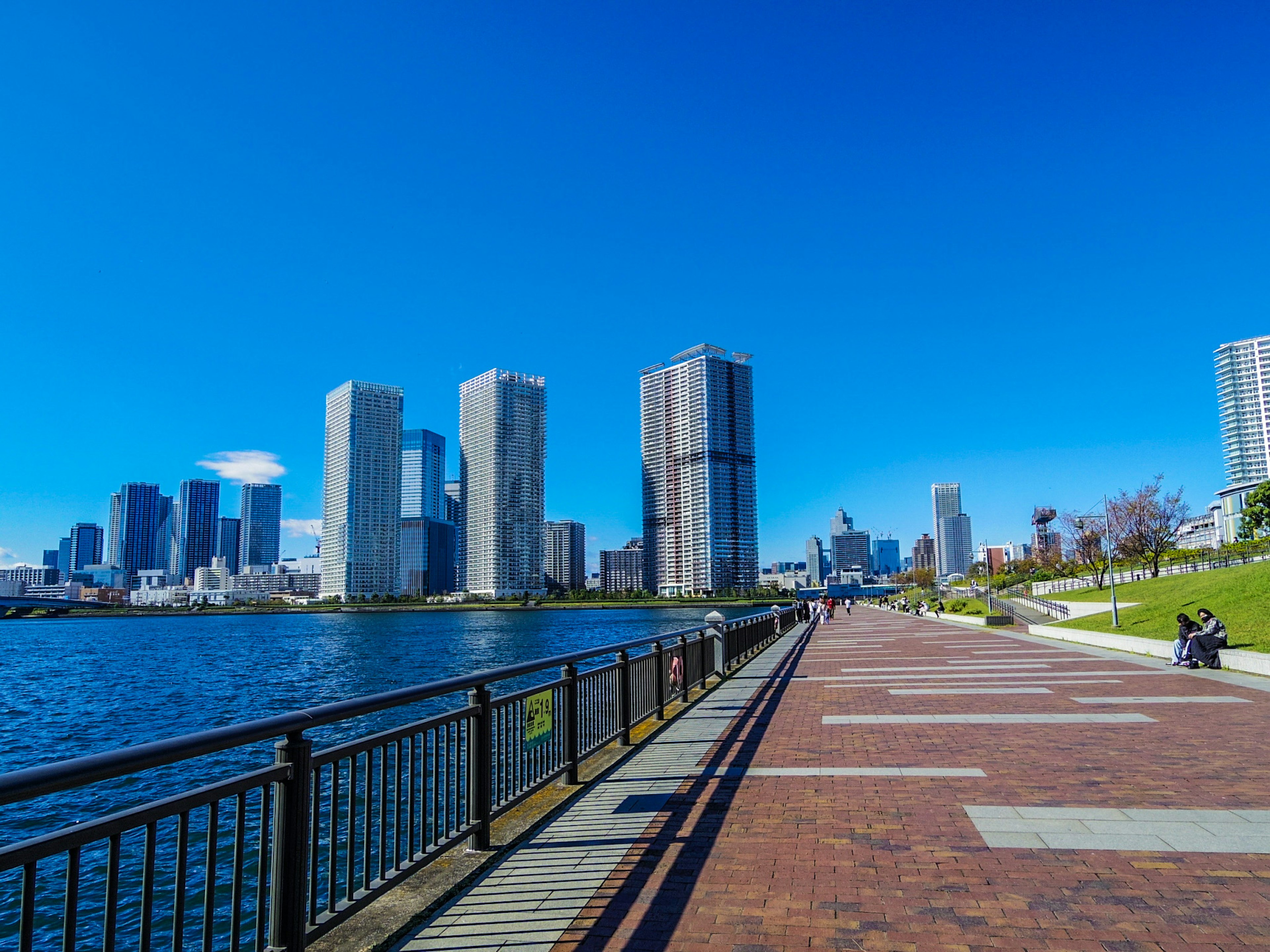 Grattacieli lungo un sentiero waterfront sotto un cielo blu chiaro