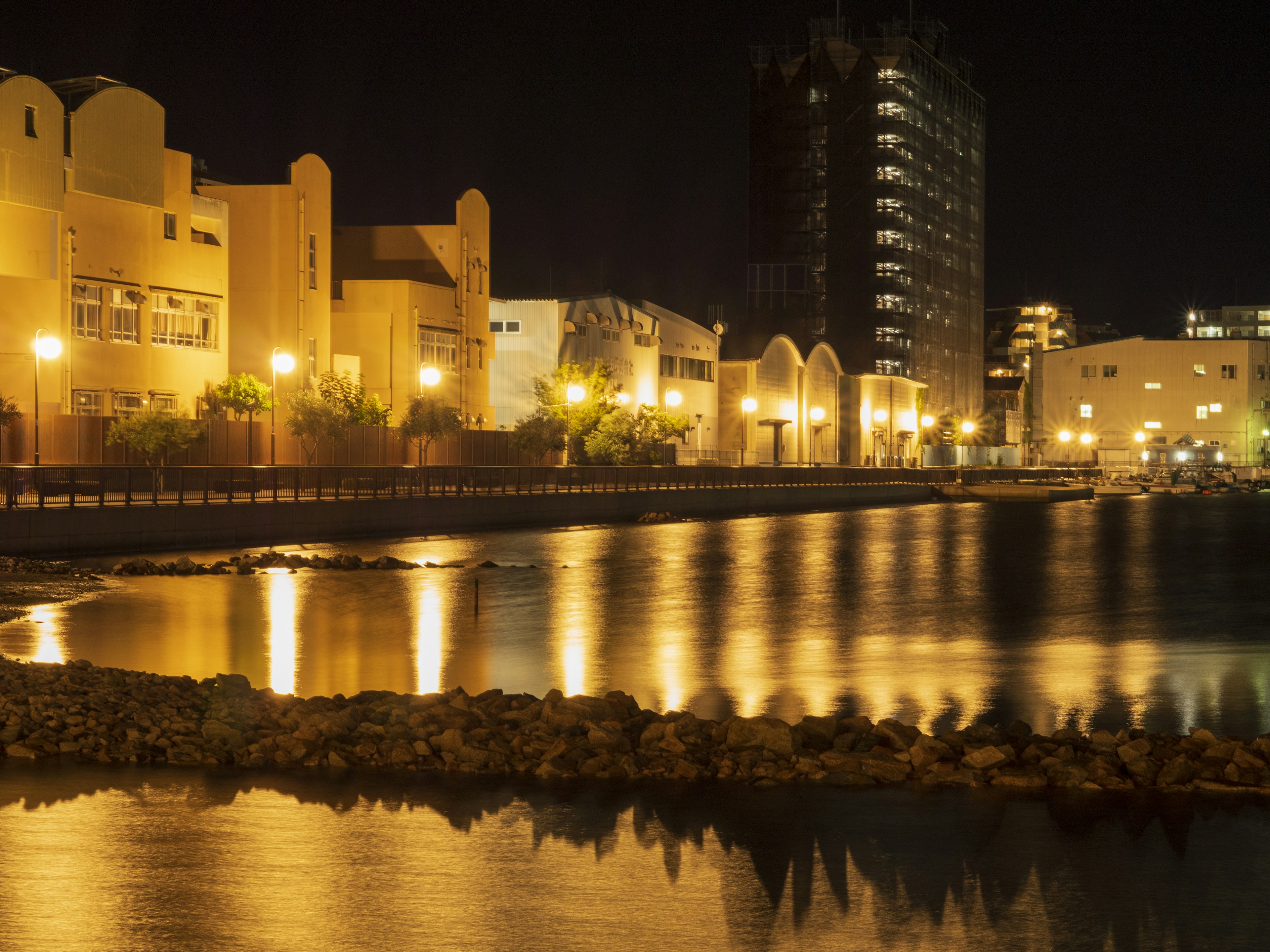 Nighttime waterfront with illuminated buildings and reflections