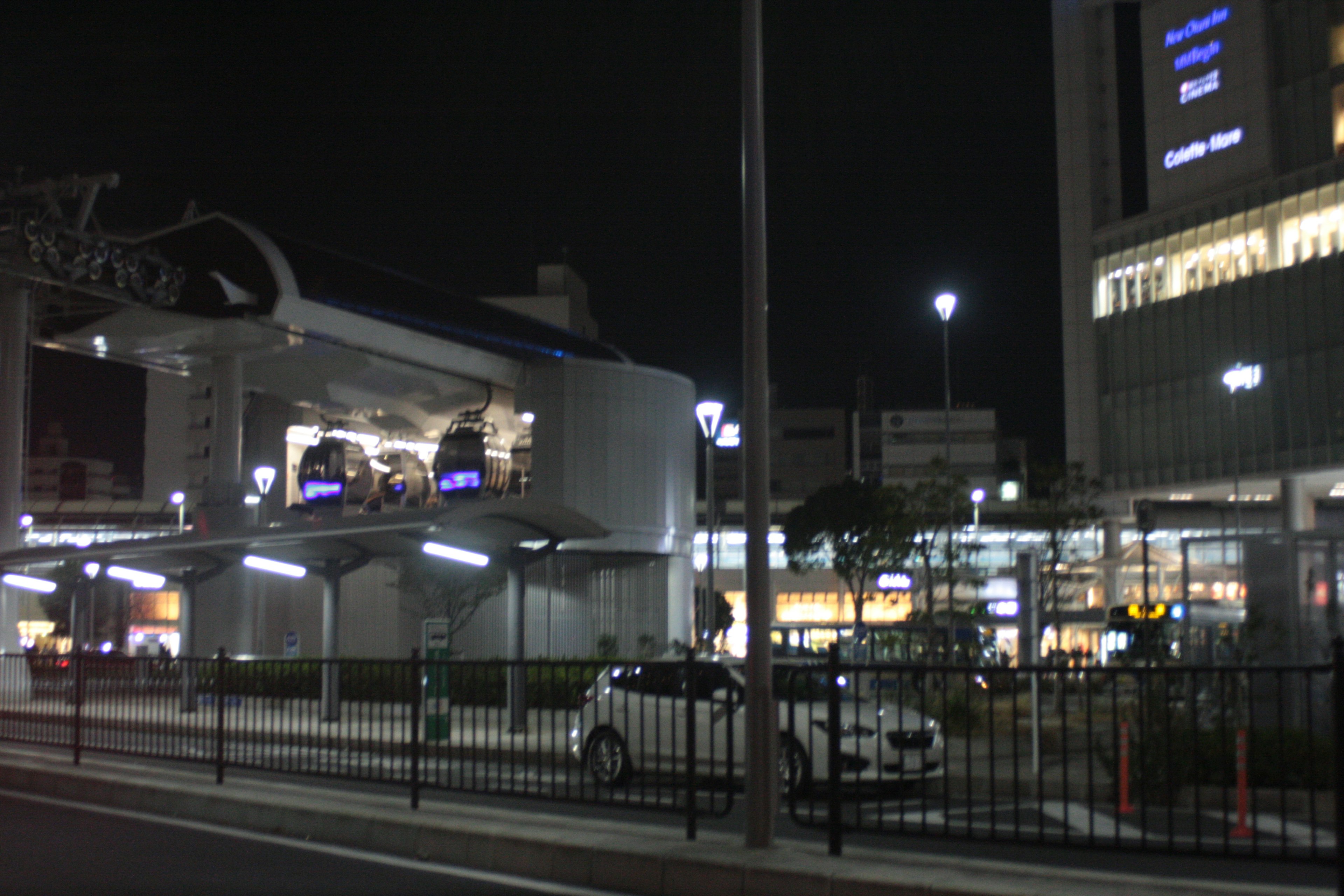 夜の街並みにある近代的な駅の外観と周囲の車両