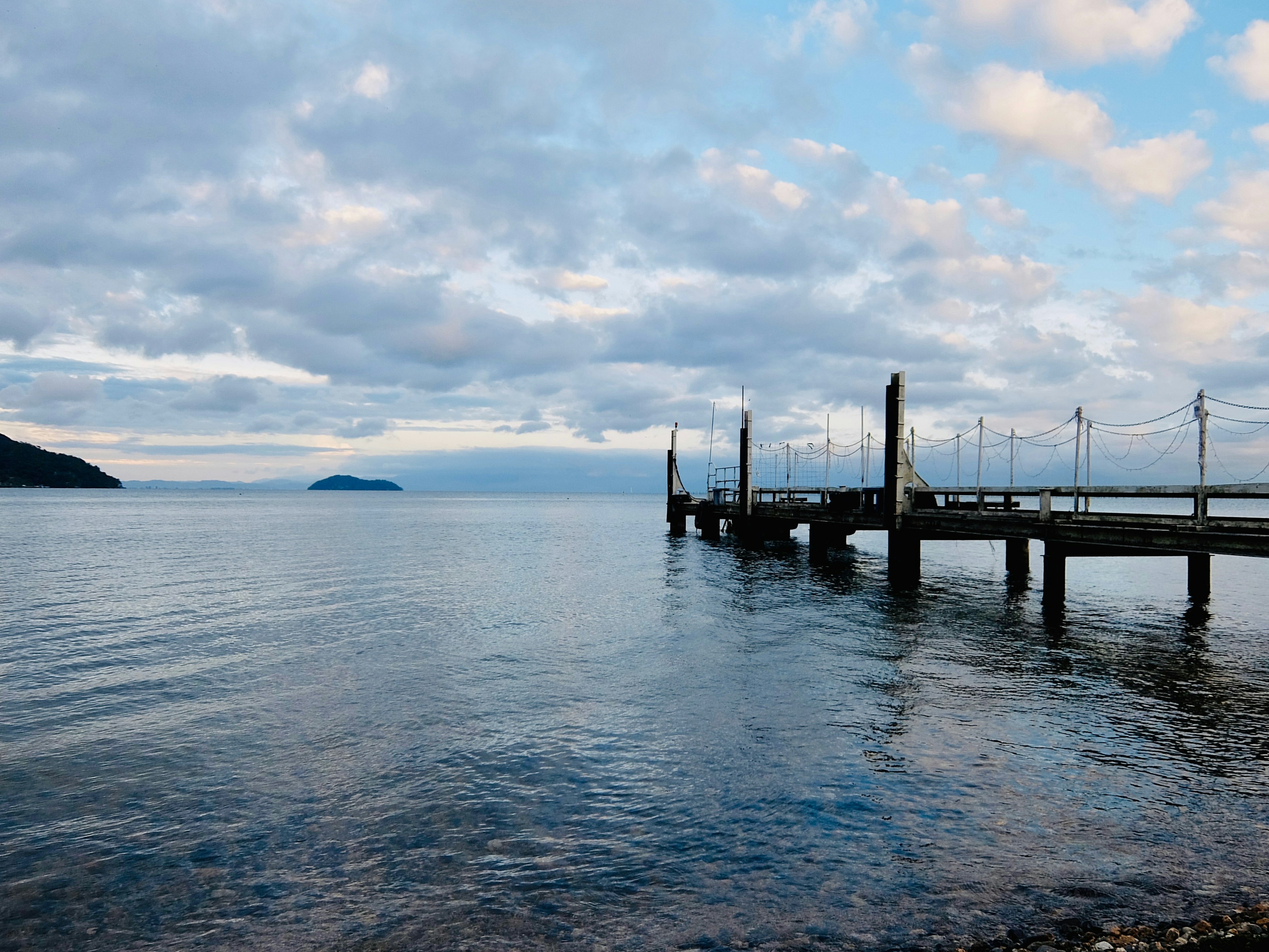 Mar tranquilo con cielo nublado y un muelle de madera