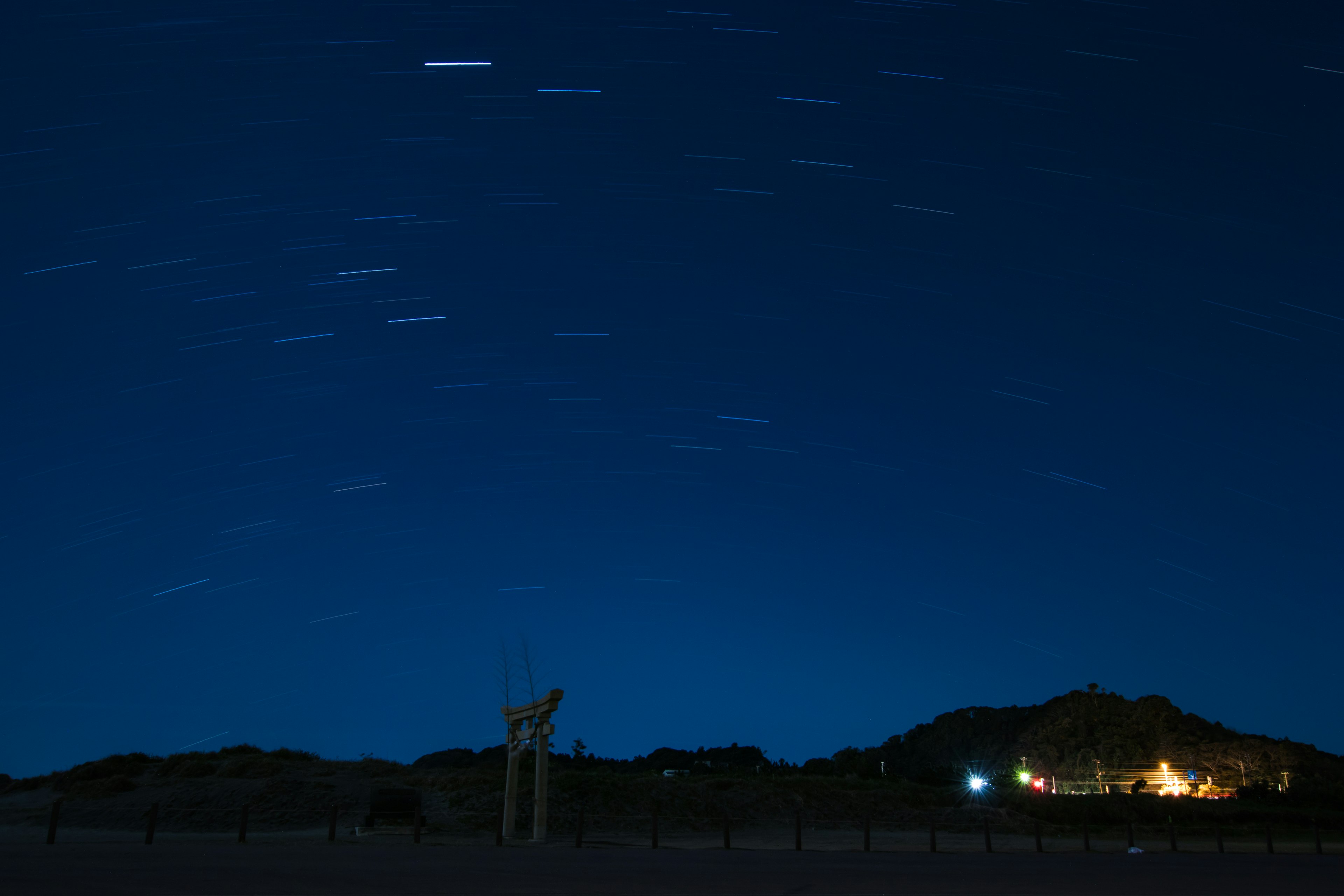 Cielo notturno con scie di stelle e silhouette di montagne