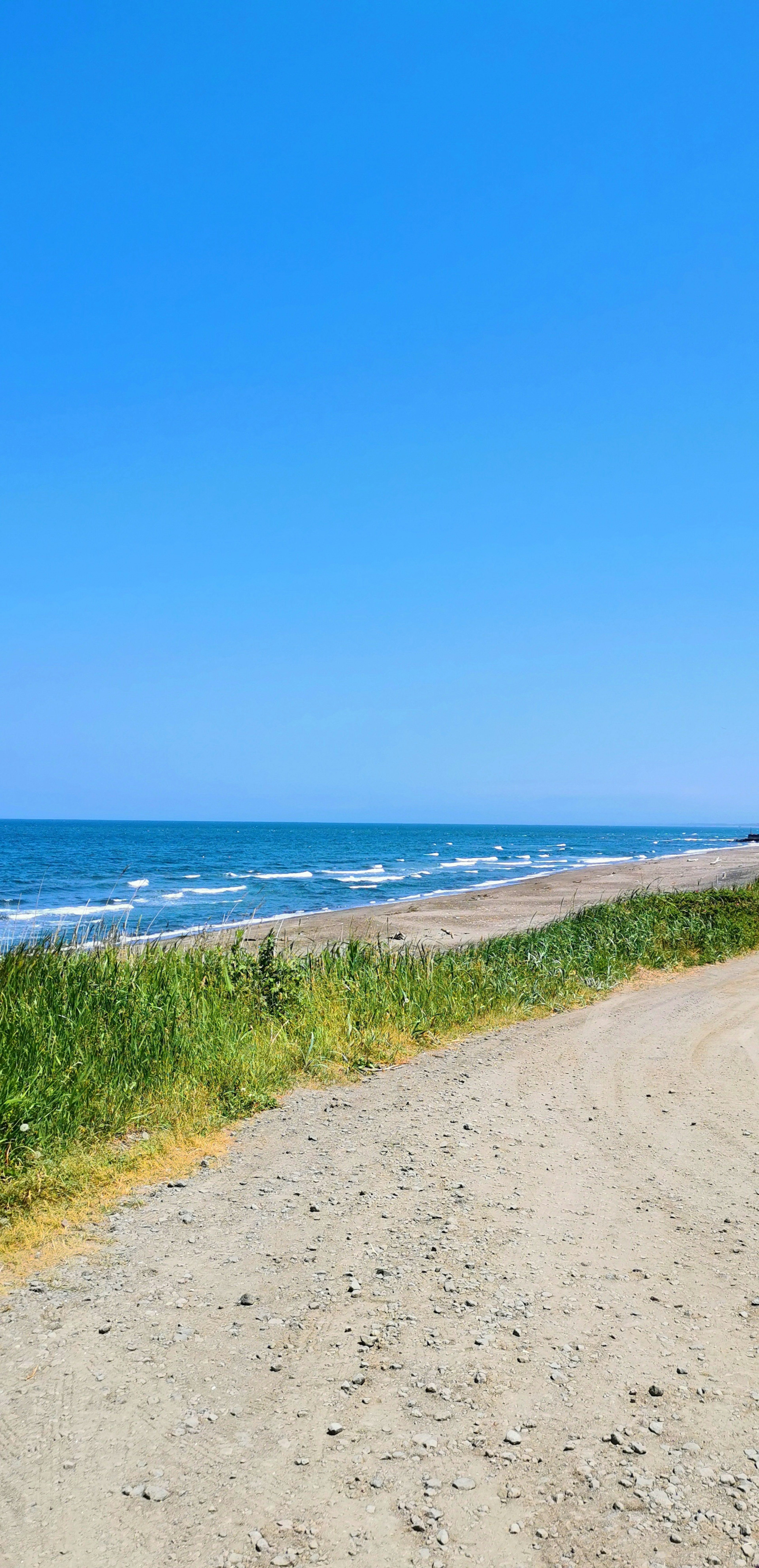 Malerscher Strandblick mit klarem blauen Himmel und Sandweg entlang der Küste