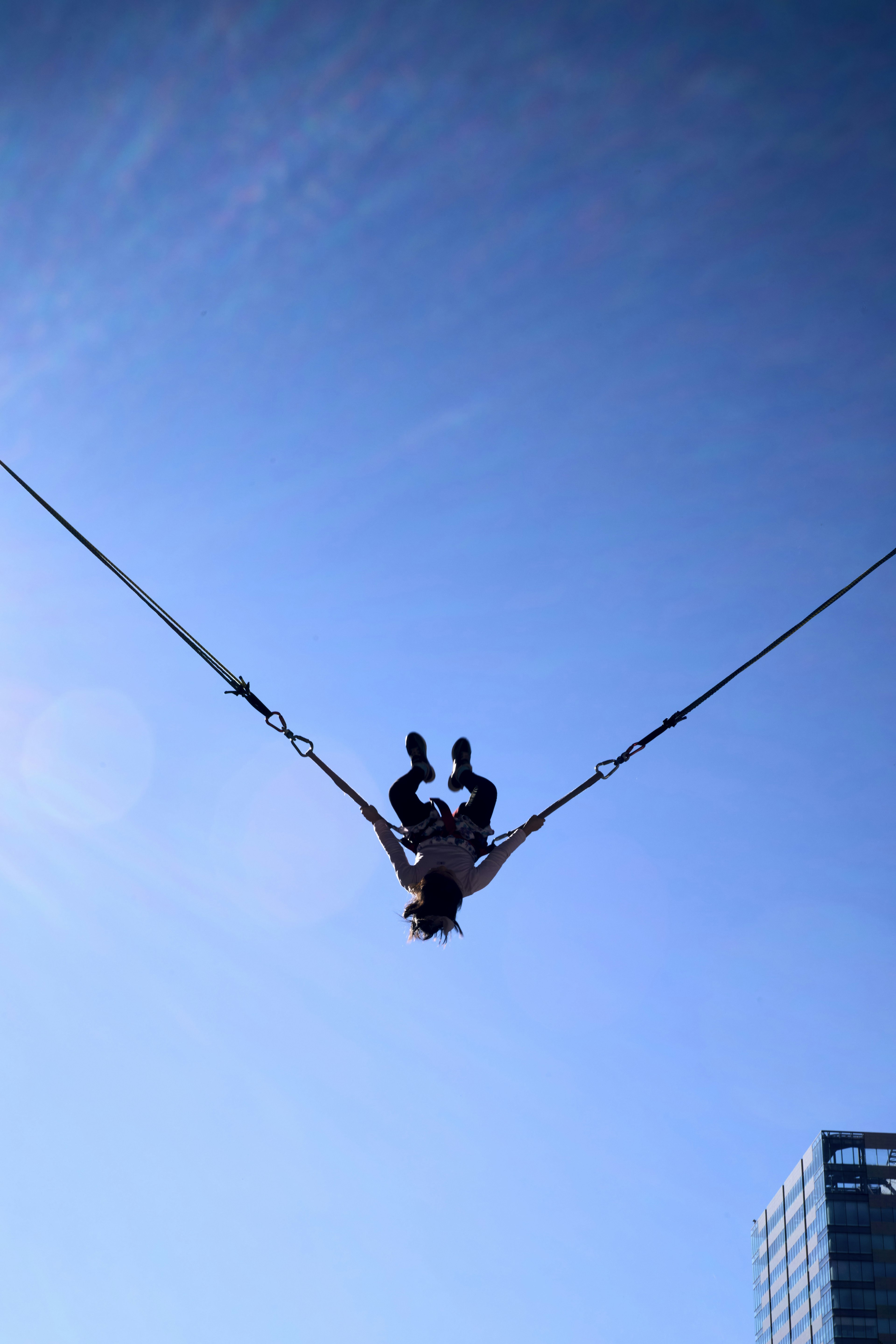 Orang yang menikmati bungee jumping di bawah langit biru