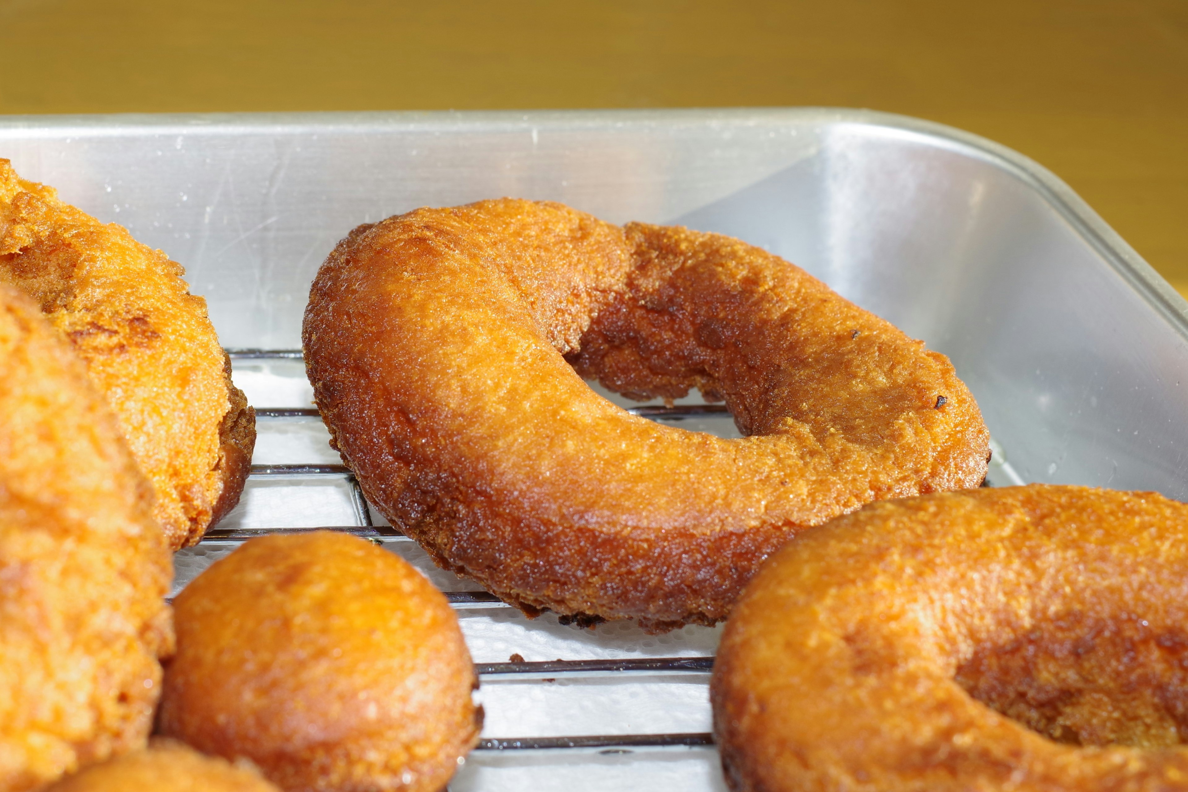 Fried donuts arranged on a cooling rack in a tray