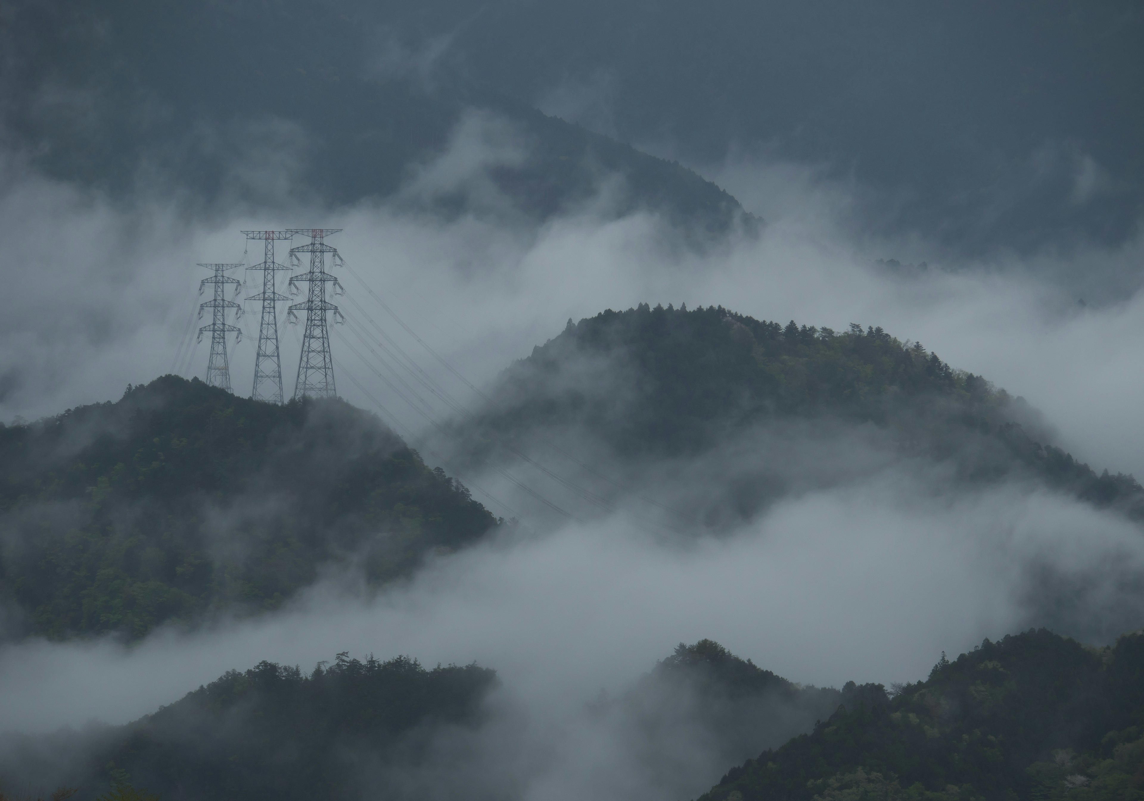 霧に包まれた山々と高圧電線の風景