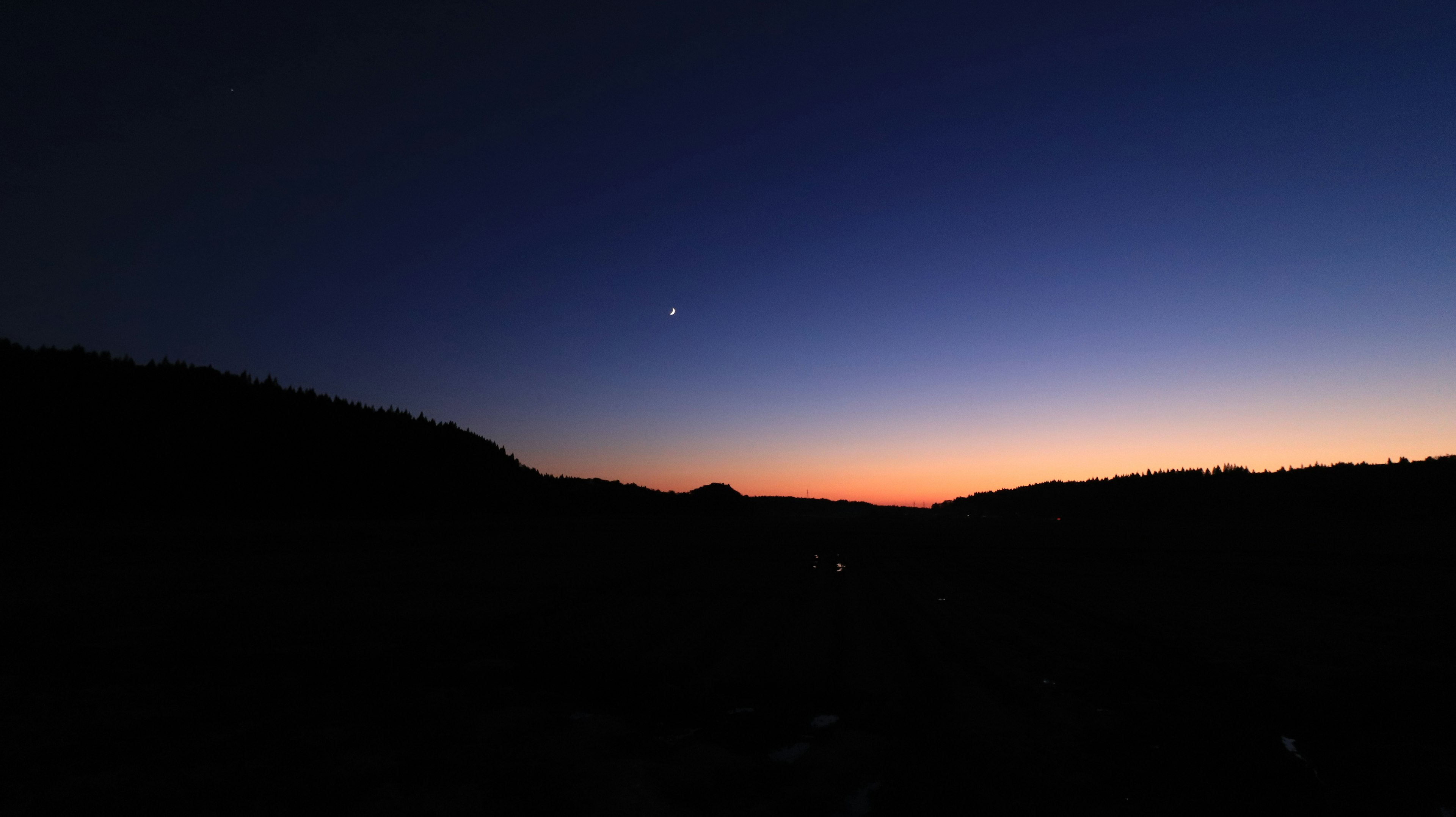 Silhouette of mountains under a dawn sky with a visible star