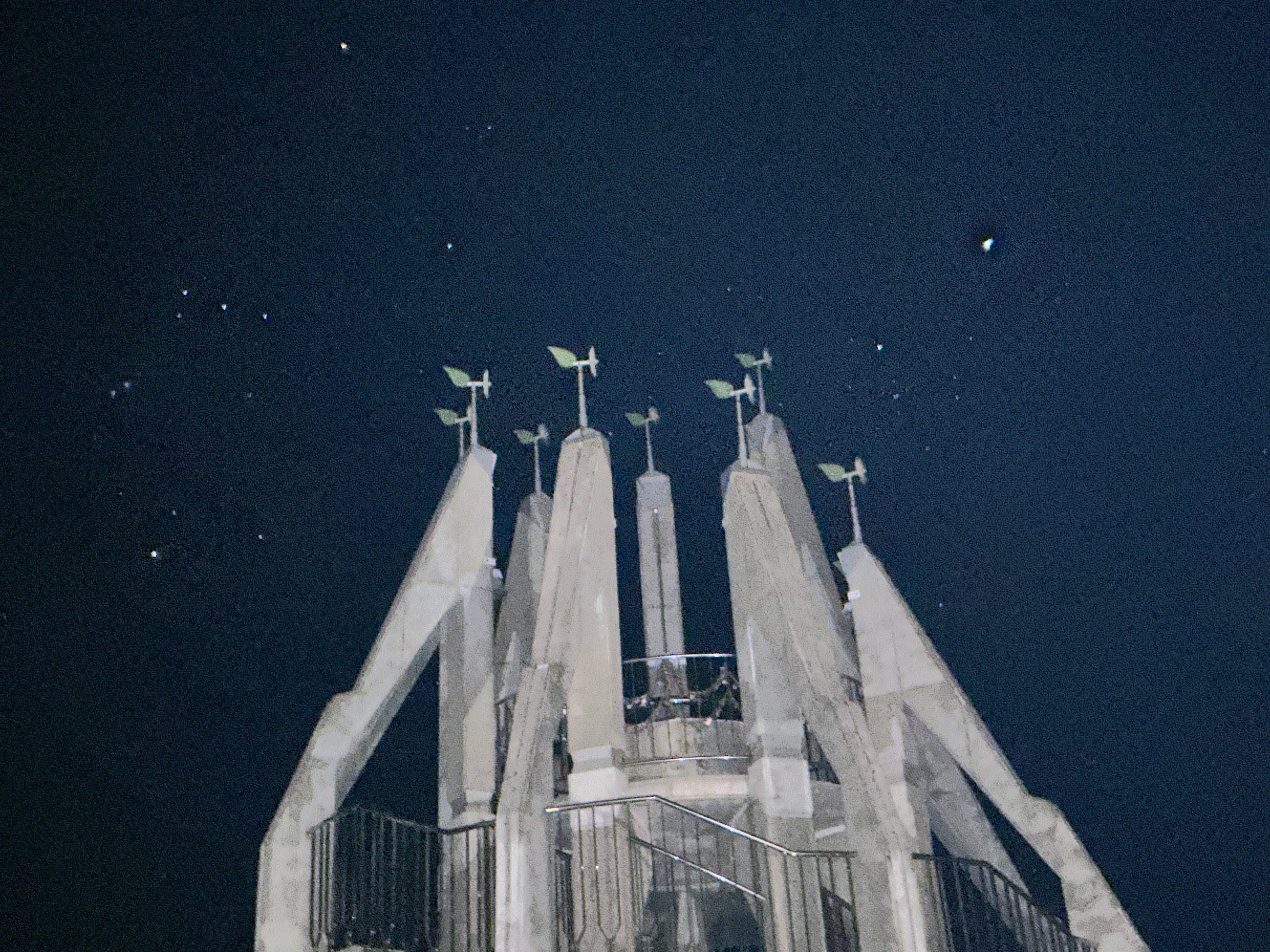 Top of a tower featuring weather vanes against a starry night sky