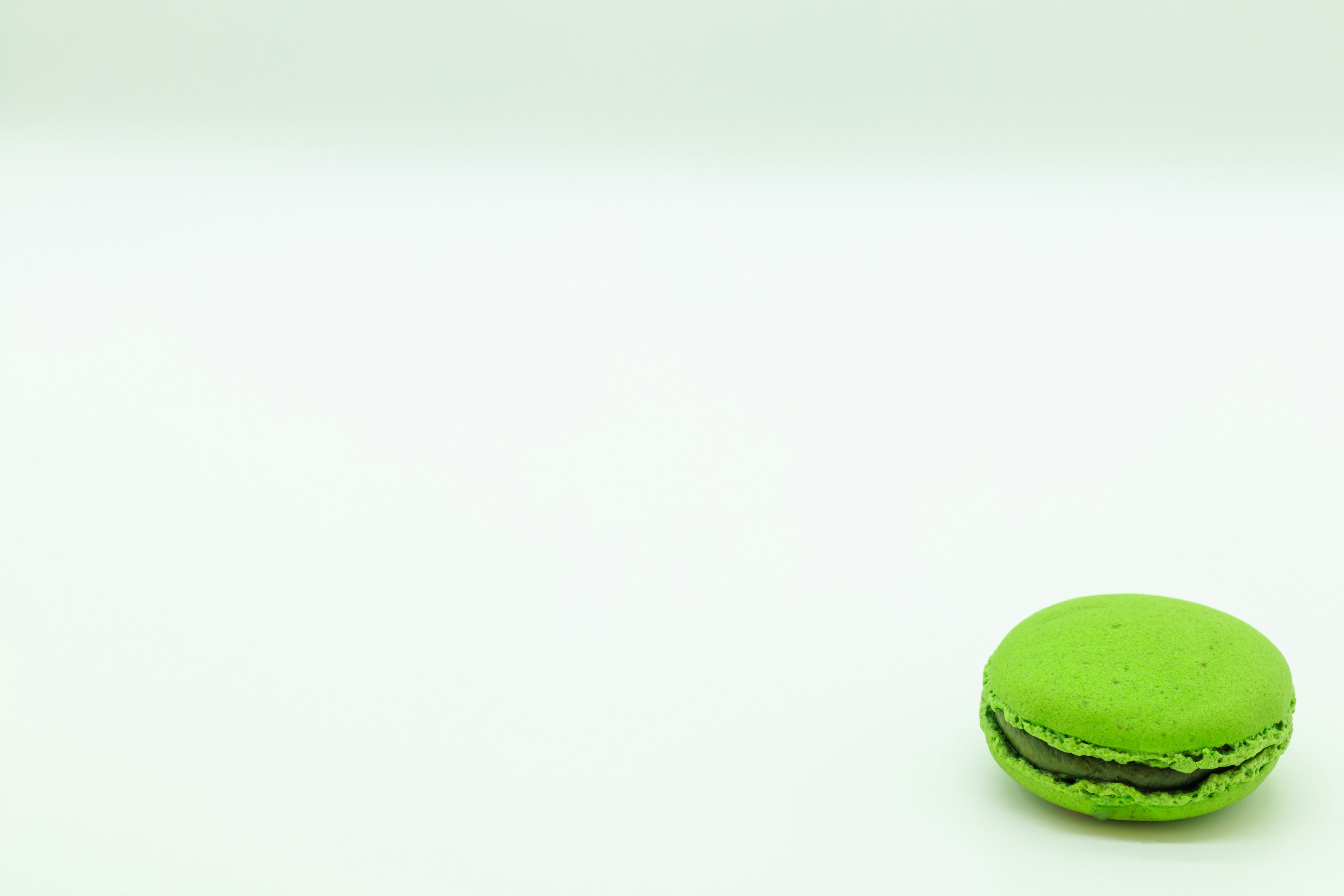 Un macaron vert posé sur un fond blanc