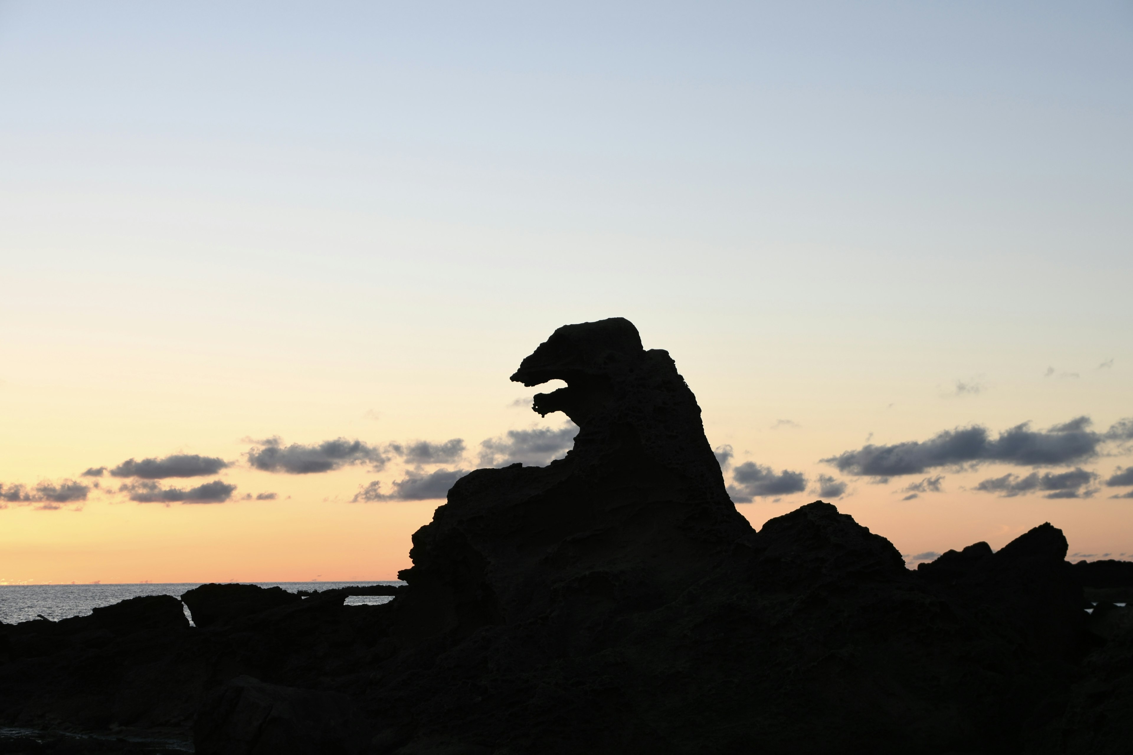 Silhouette eines Rocks, der einem Tier ähnelt, vor einem Sonnenuntergangshimmel