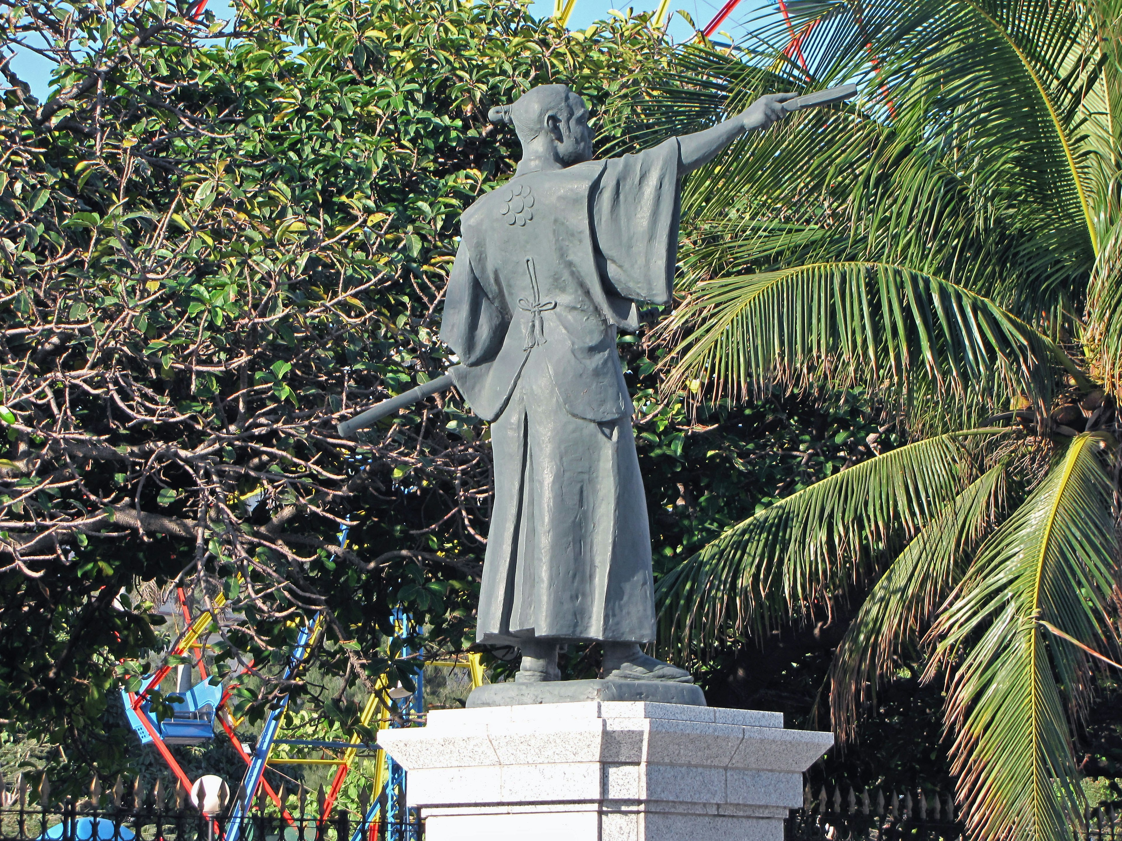 Statue en bronze pointant avec de la verdure en arrière-plan