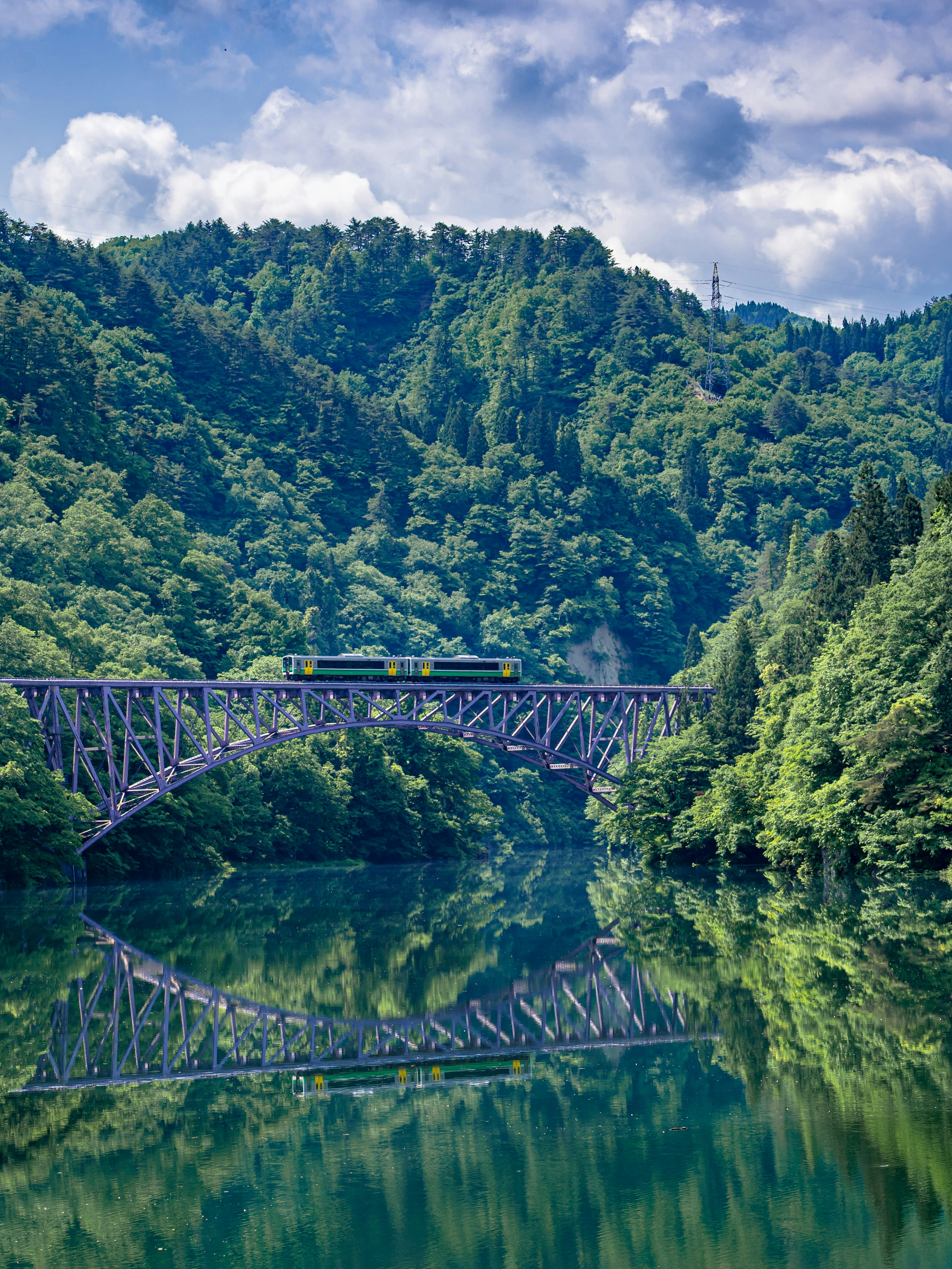 Vista escénica de un puente de metal sobre un río rodeado de montañas verdes