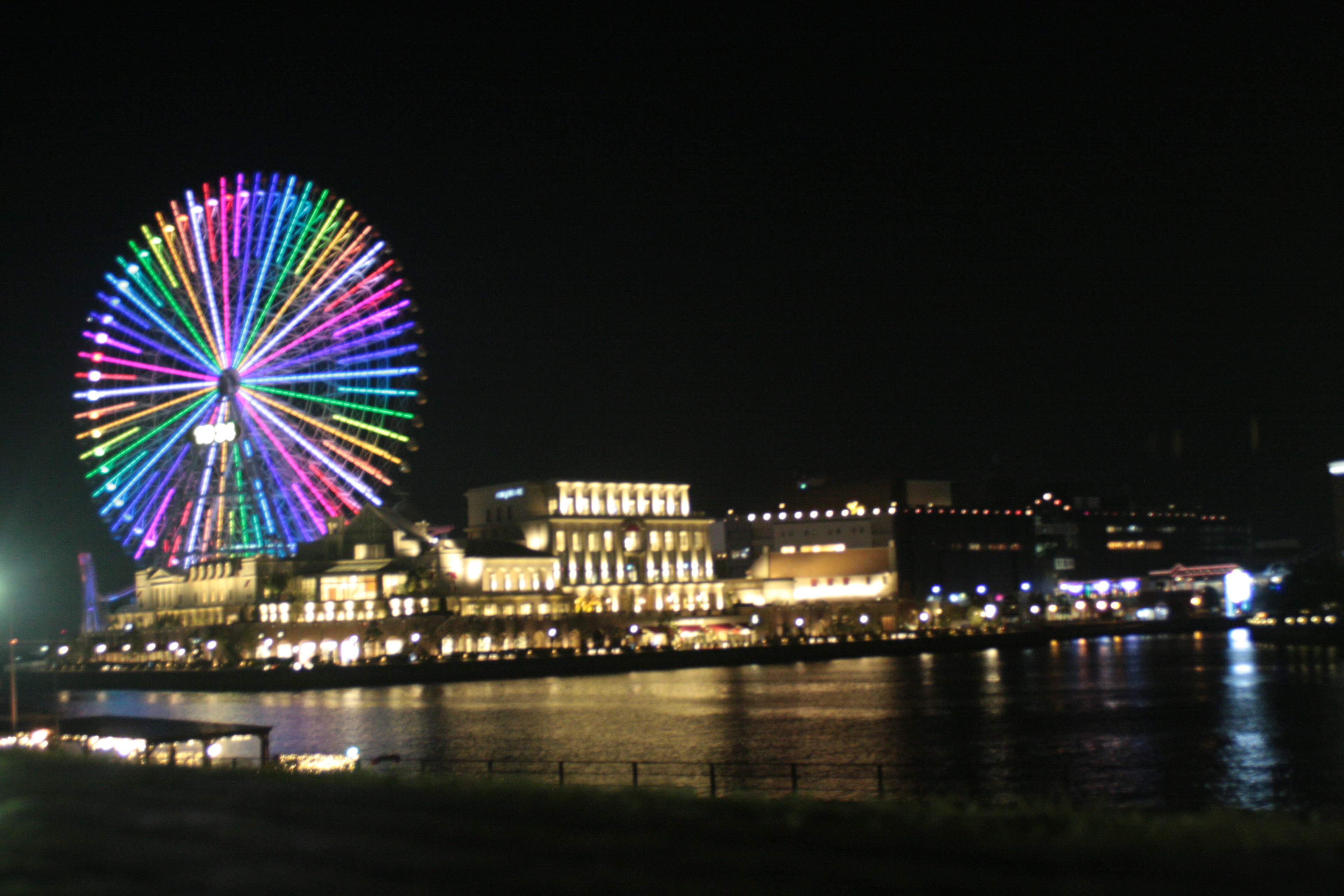 夜間色彩繽紛的摩天輪和河岸建築