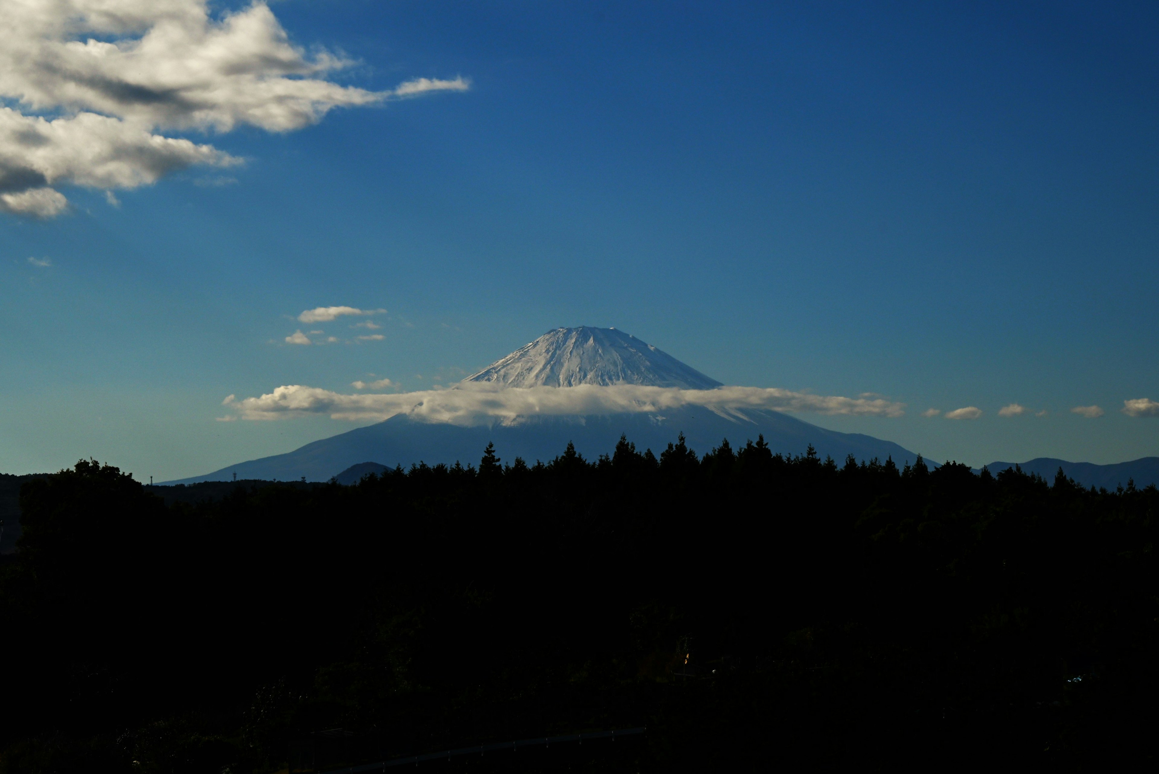 在晴朗的蓝天下，富士山的壮丽景色与云朵