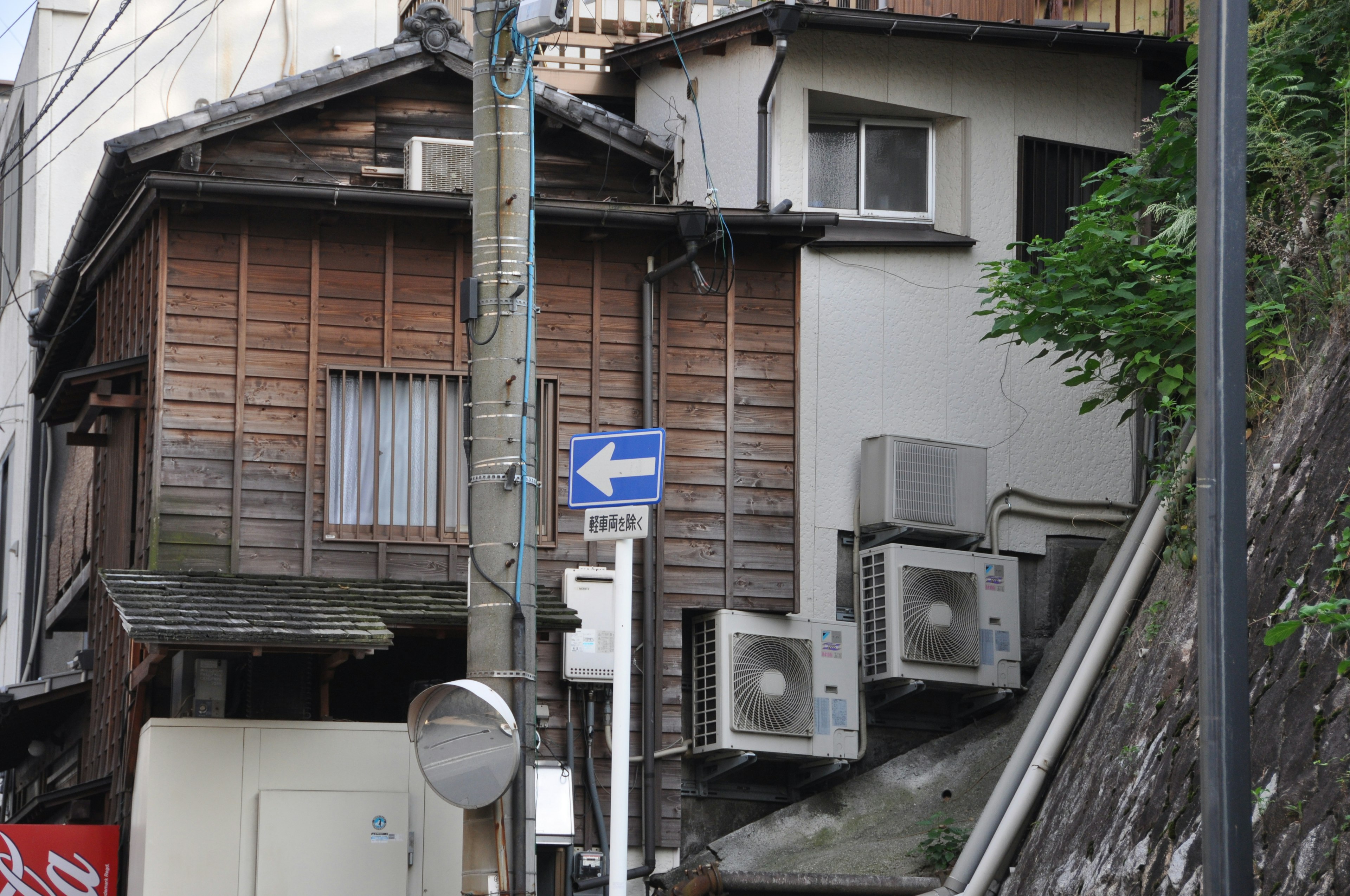 Street view featuring an old wooden house with air conditioning units