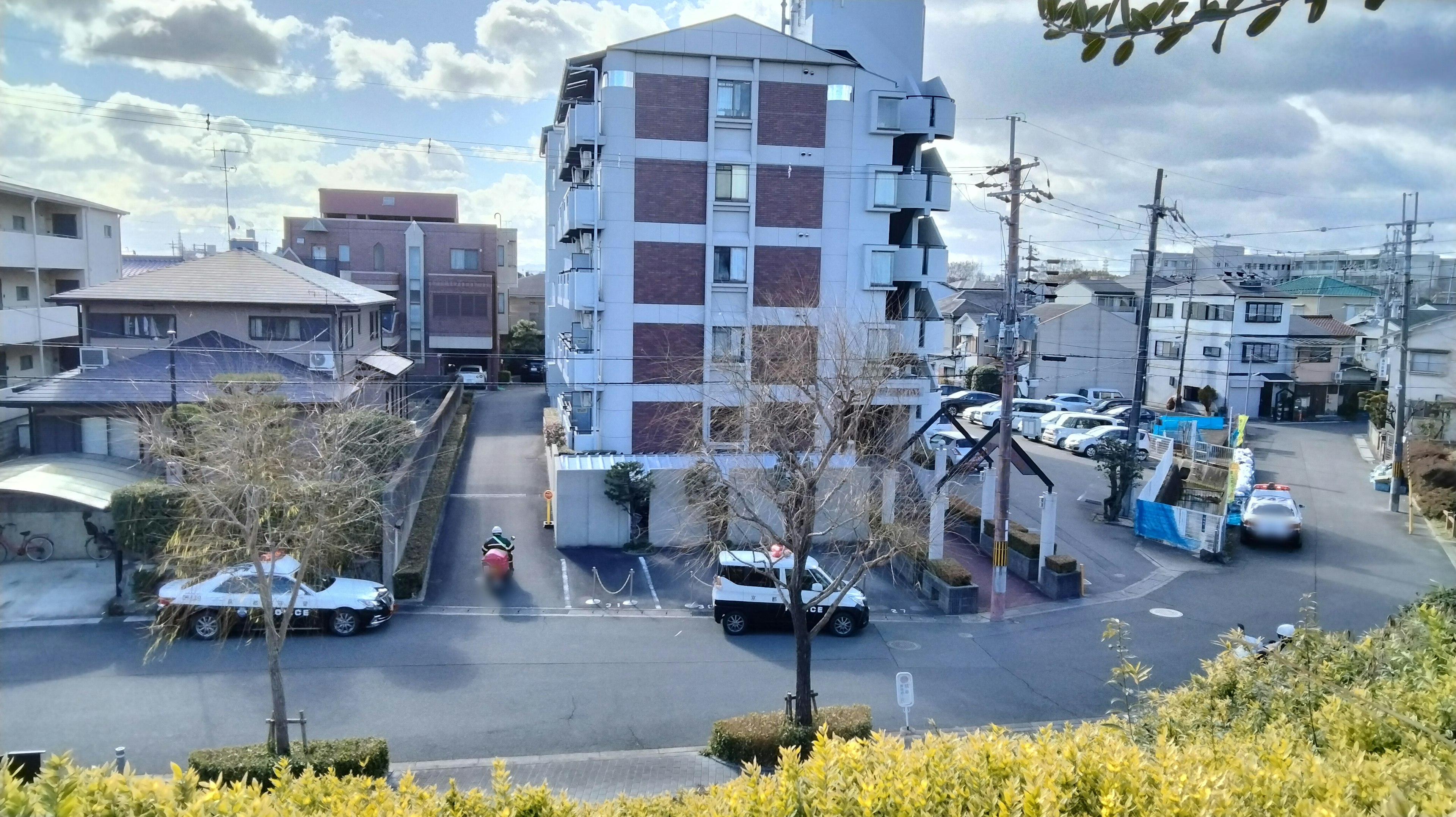 View of a residential area featuring a four-story building and surrounding cars