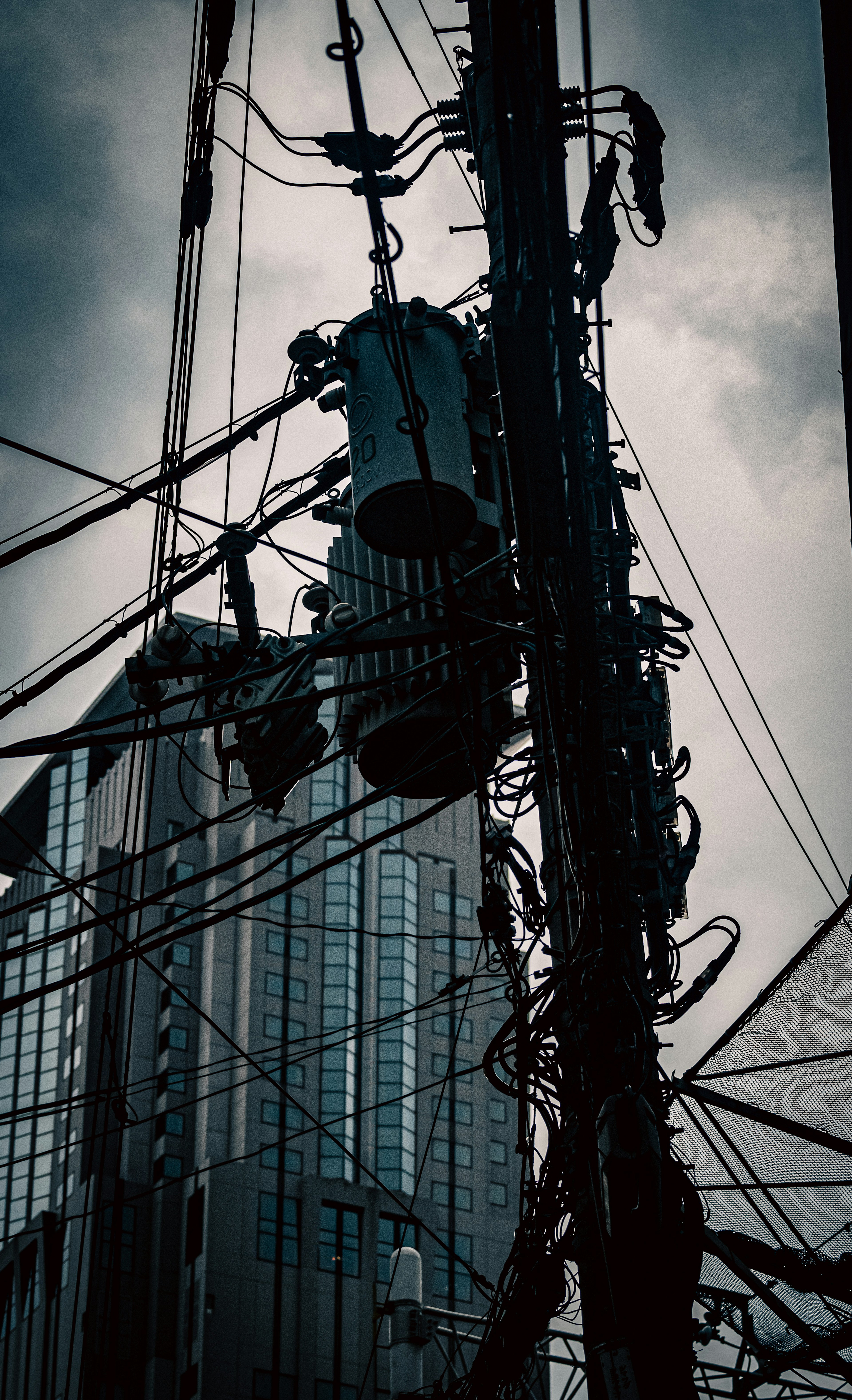 Close-up image of power lines and pole behind a building