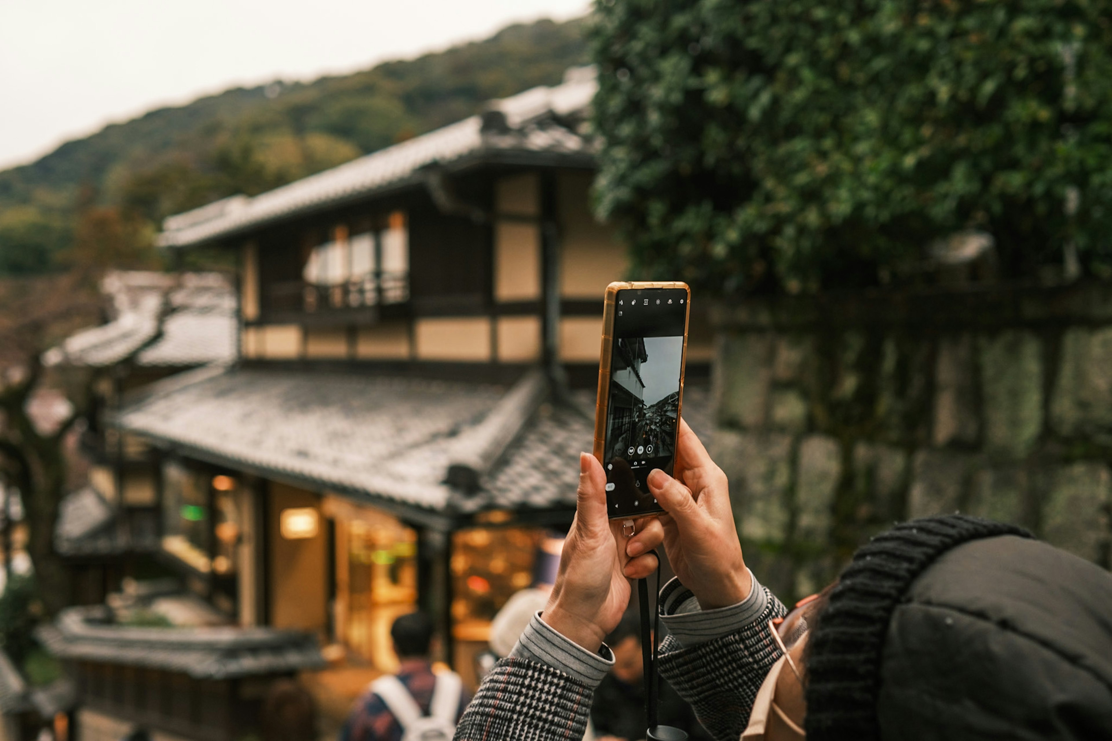 人がスマートフォンで伝統的な日本の建物を撮影しているシーン