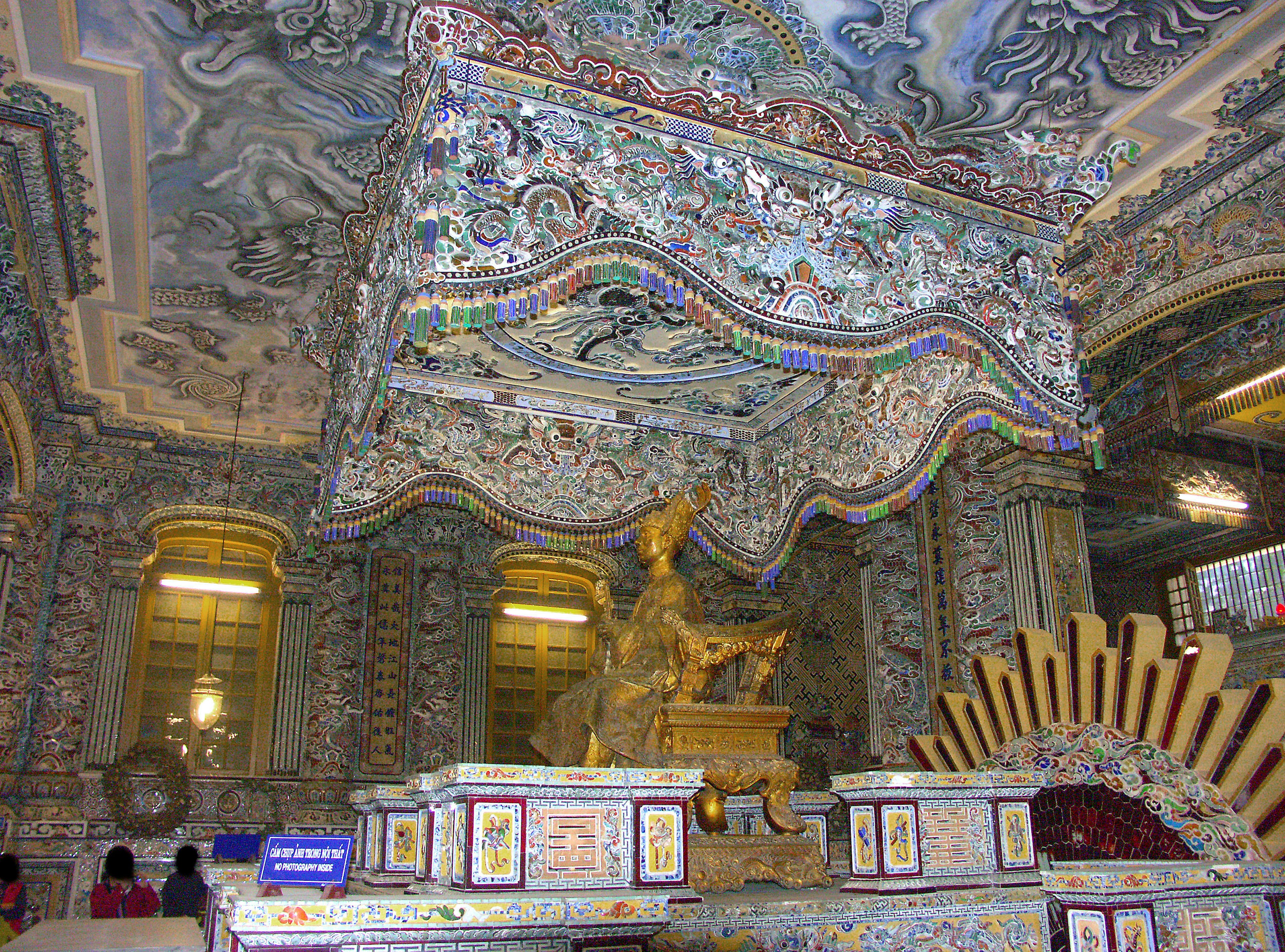 Interior de una habitación lujosamente decorada con patrones intrincados en las paredes y el techo con una escultura dorada destacada