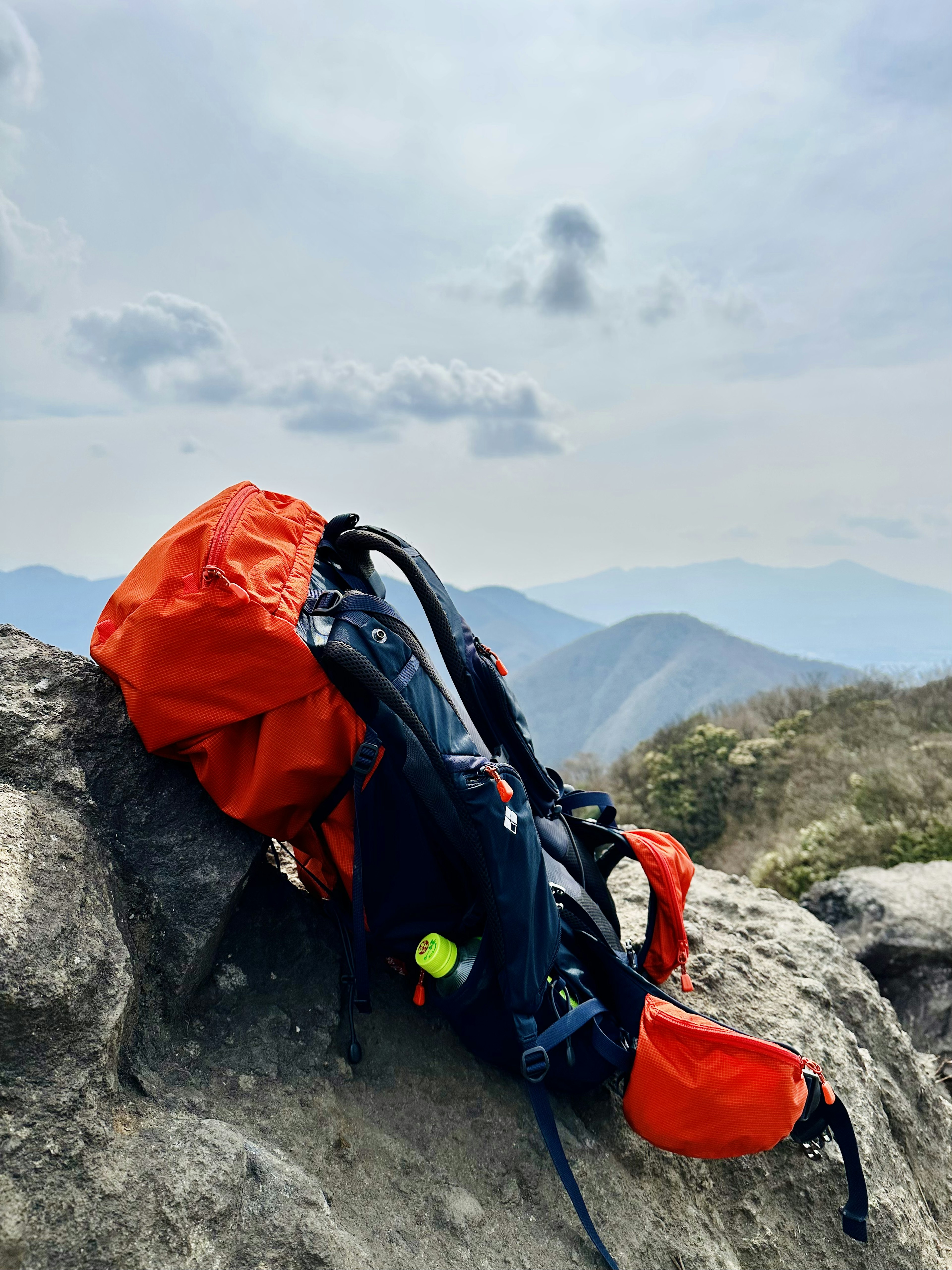 Sac à dos rouge reposant sur une roche avec des montagnes en arrière-plan