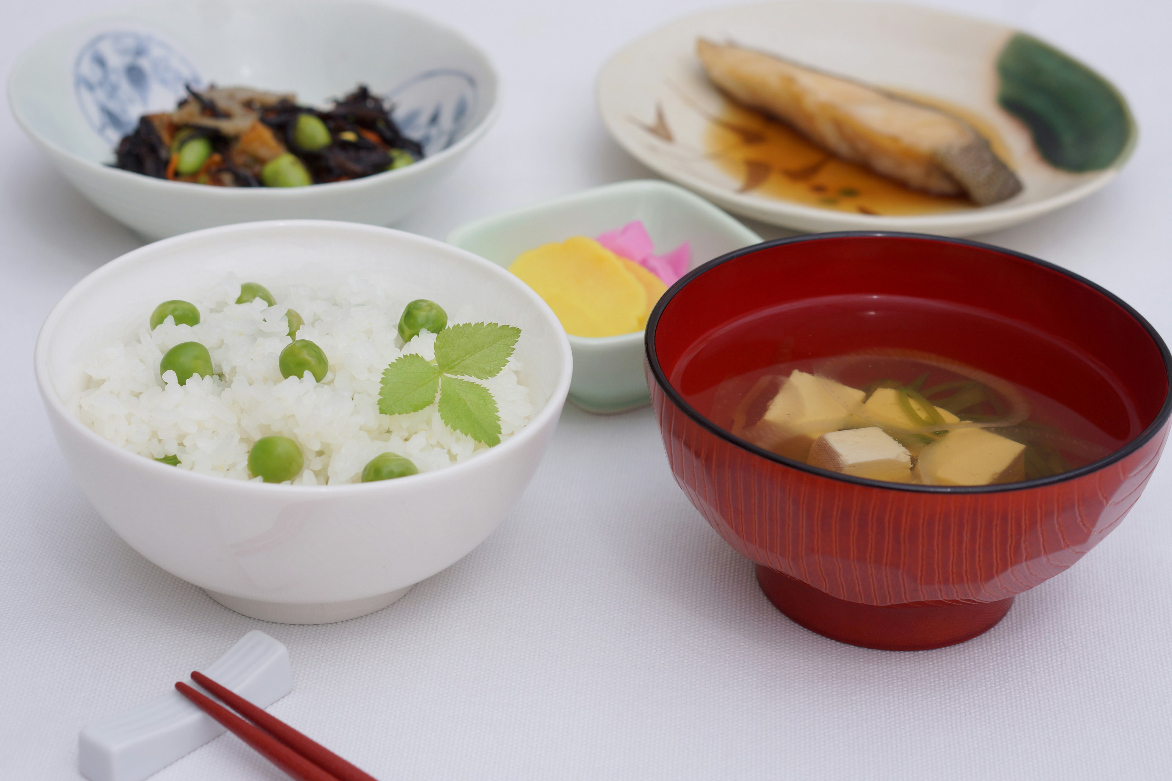 Traditional Japanese meal presentation featuring white rice with edamame miso soup grilled fish and pickles