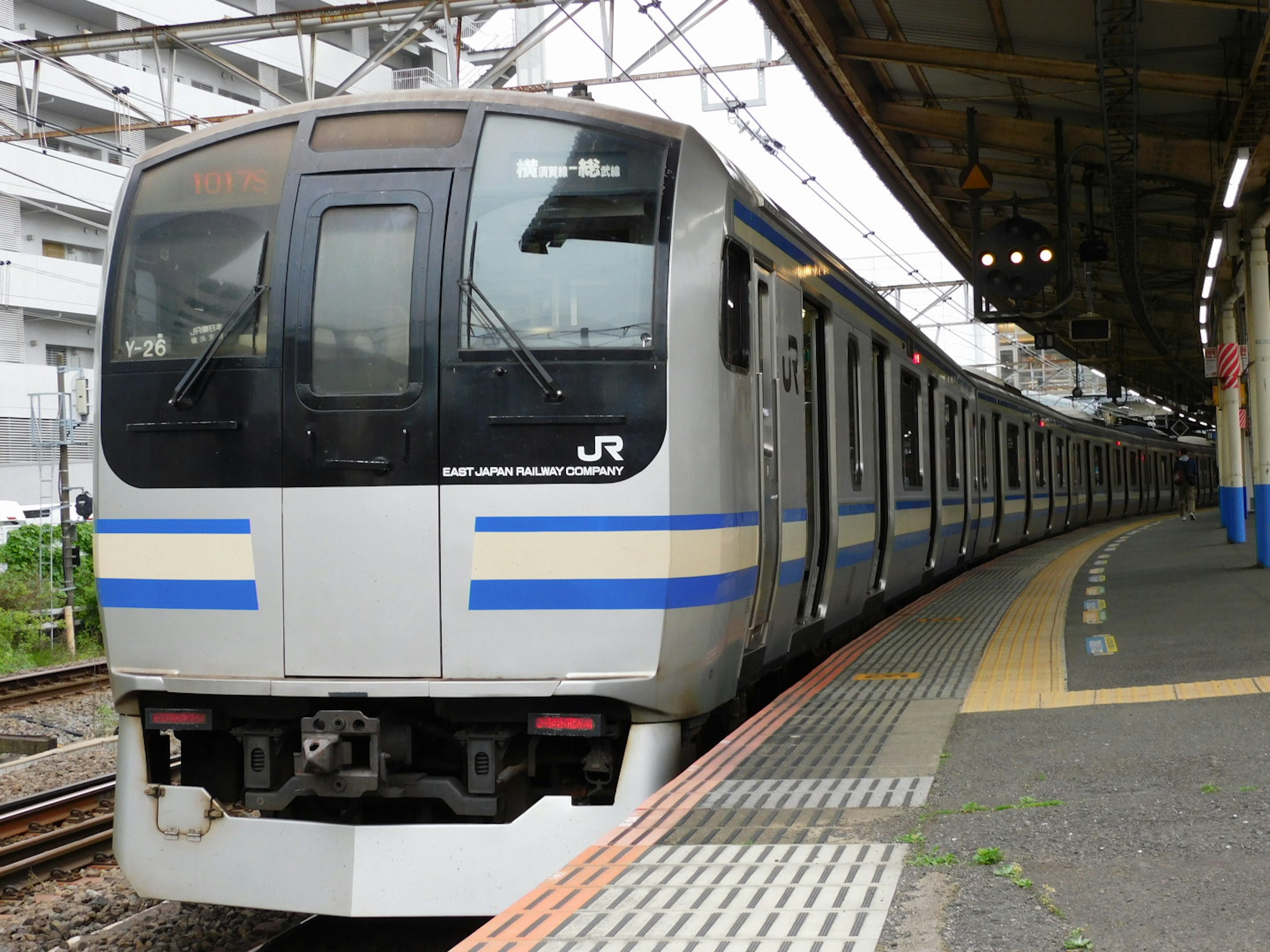 Japanischer Zug mit blauen Streifen, der an einem Bahnhof hält