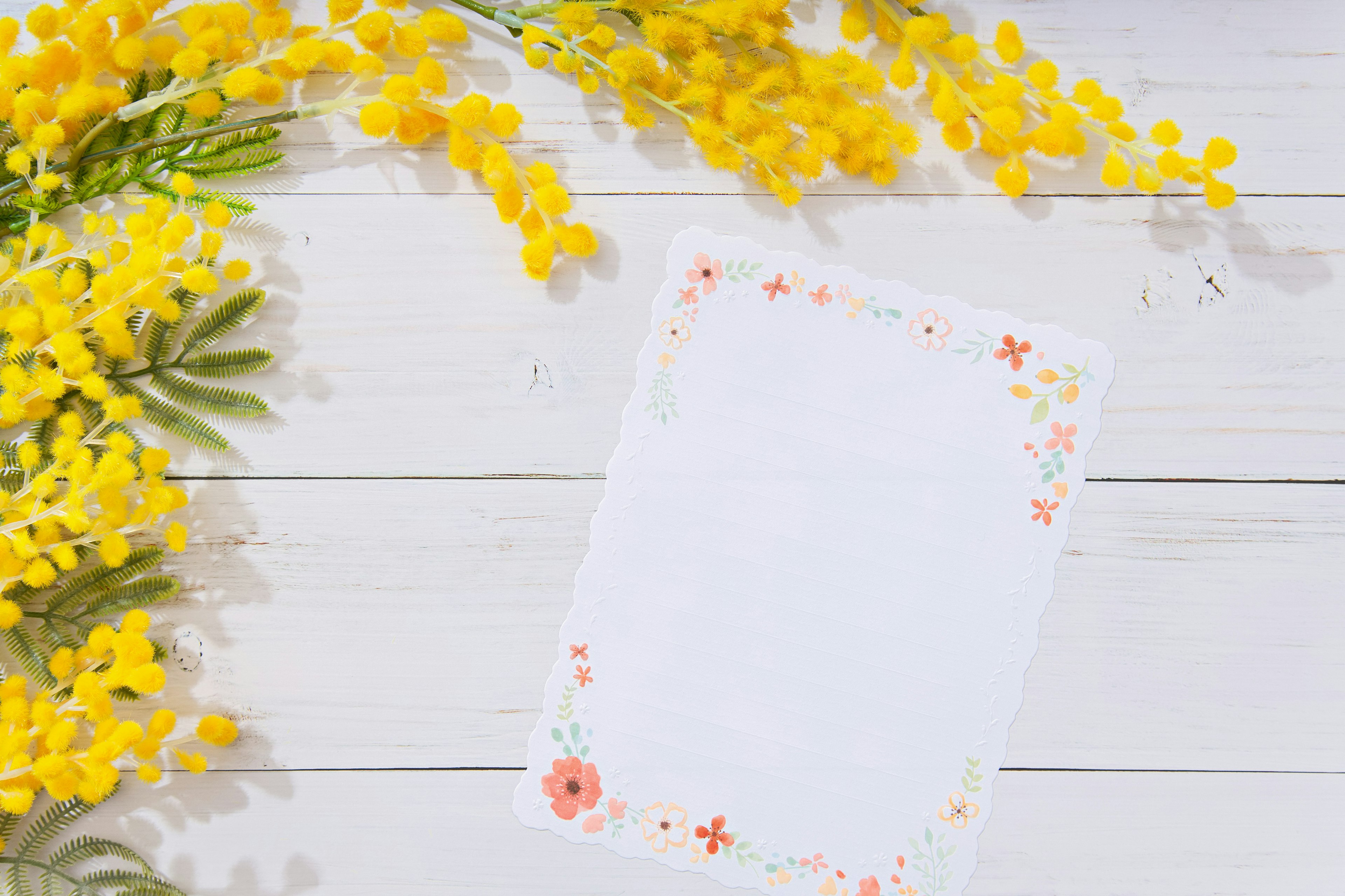 Un papier blanc entouré de décorations florales colorées avec des fleurs jaunes