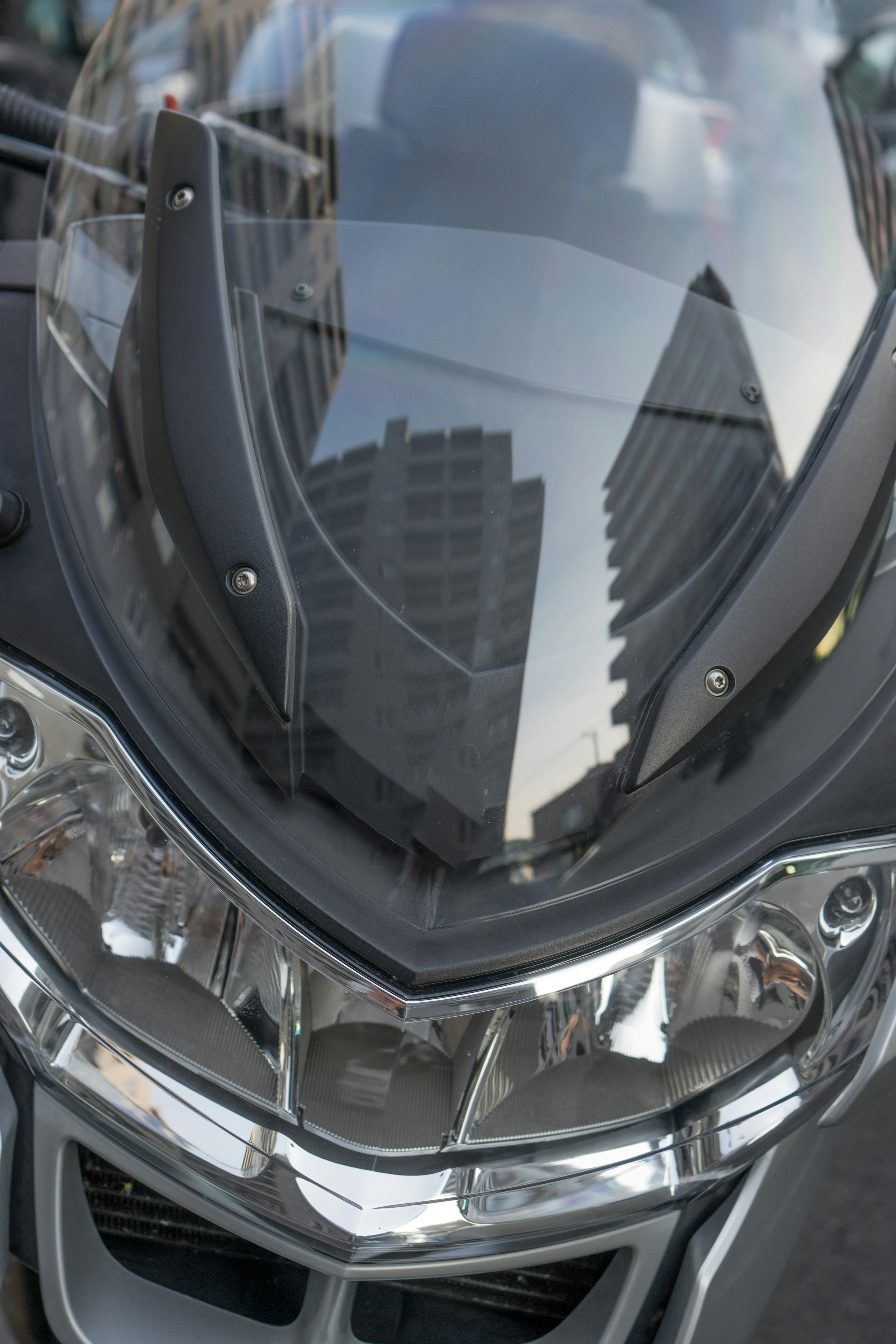 Close-up of a motorcycle front featuring reflective headlights and a windshield